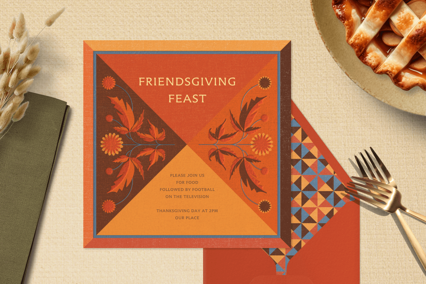 An orange Friendsgiving invitation with folk art illustrations in for diagonal quadrants next to a matching envelope and Thanksgiving table items.