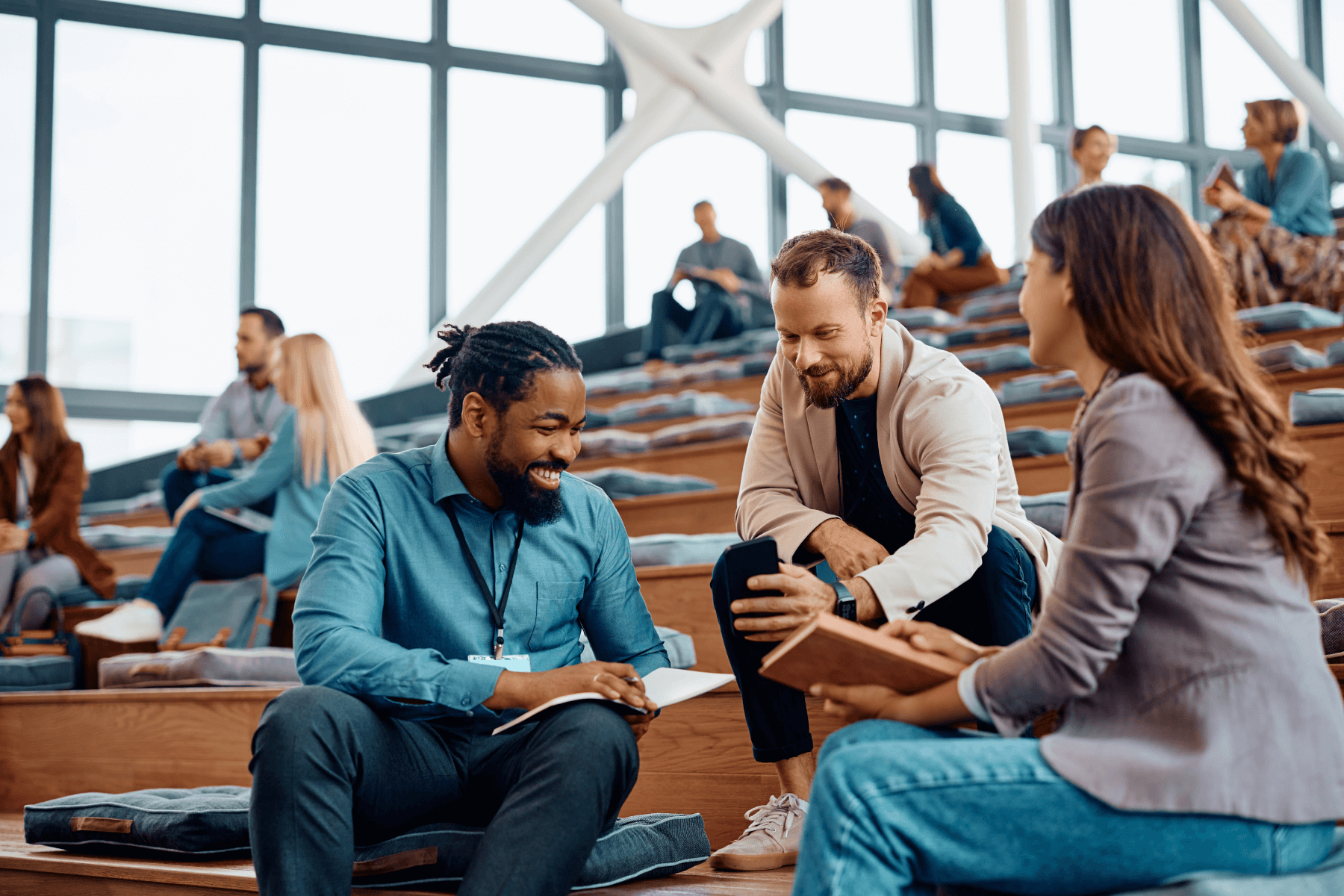 Two men and a woman sitting on steps talking.