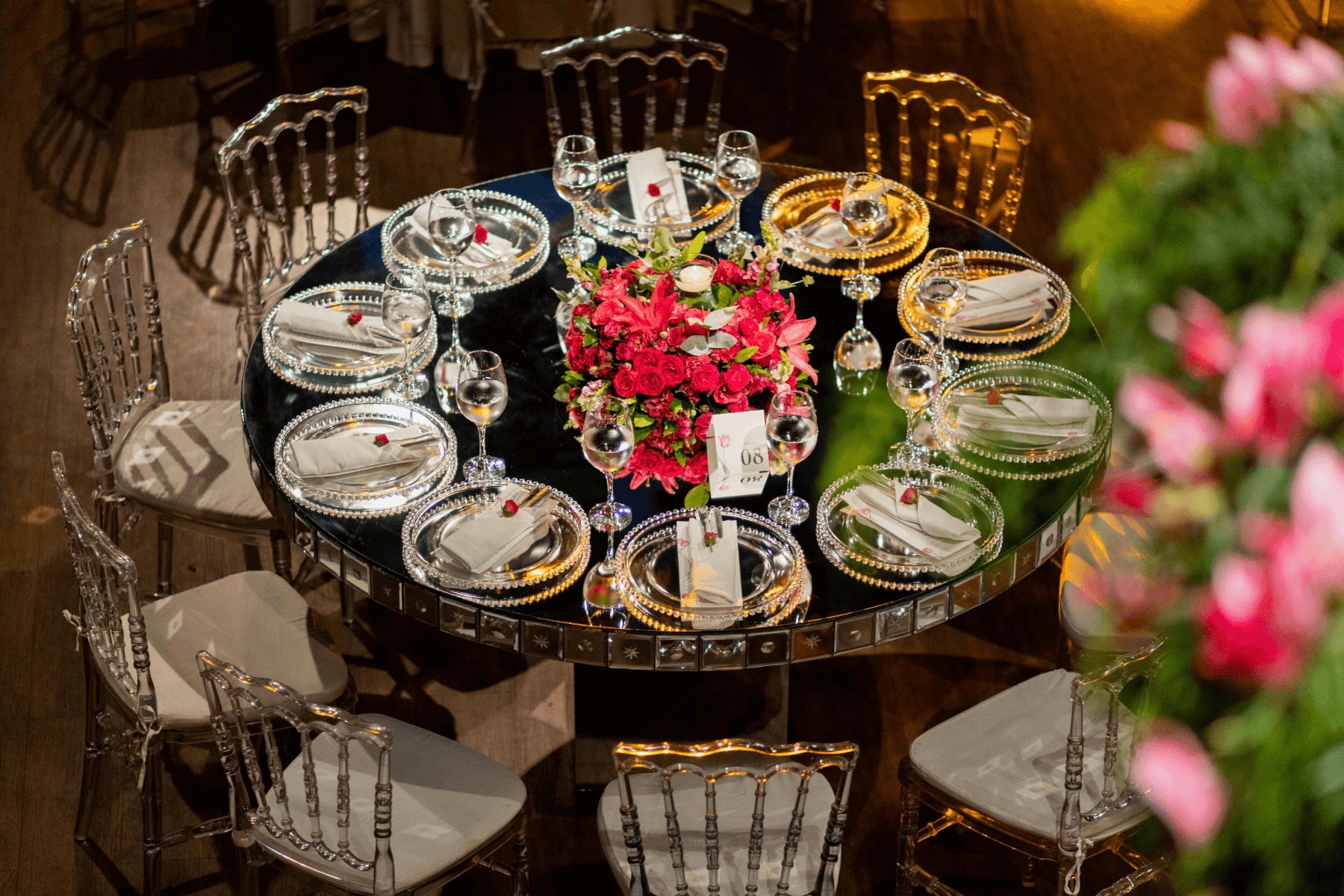 A round table set for a formal dinner surrounded by metallic chairs.