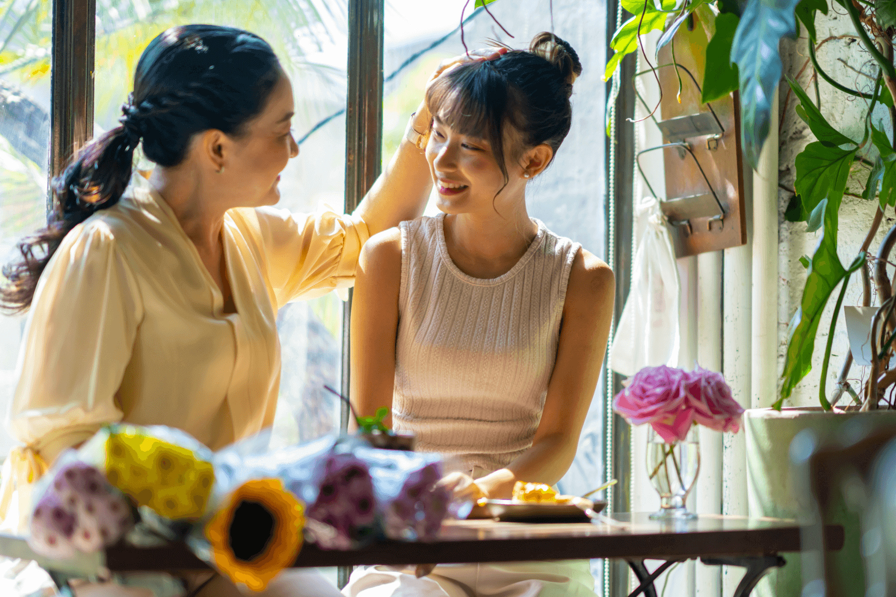 Two women smile as one touches the other’s hair.