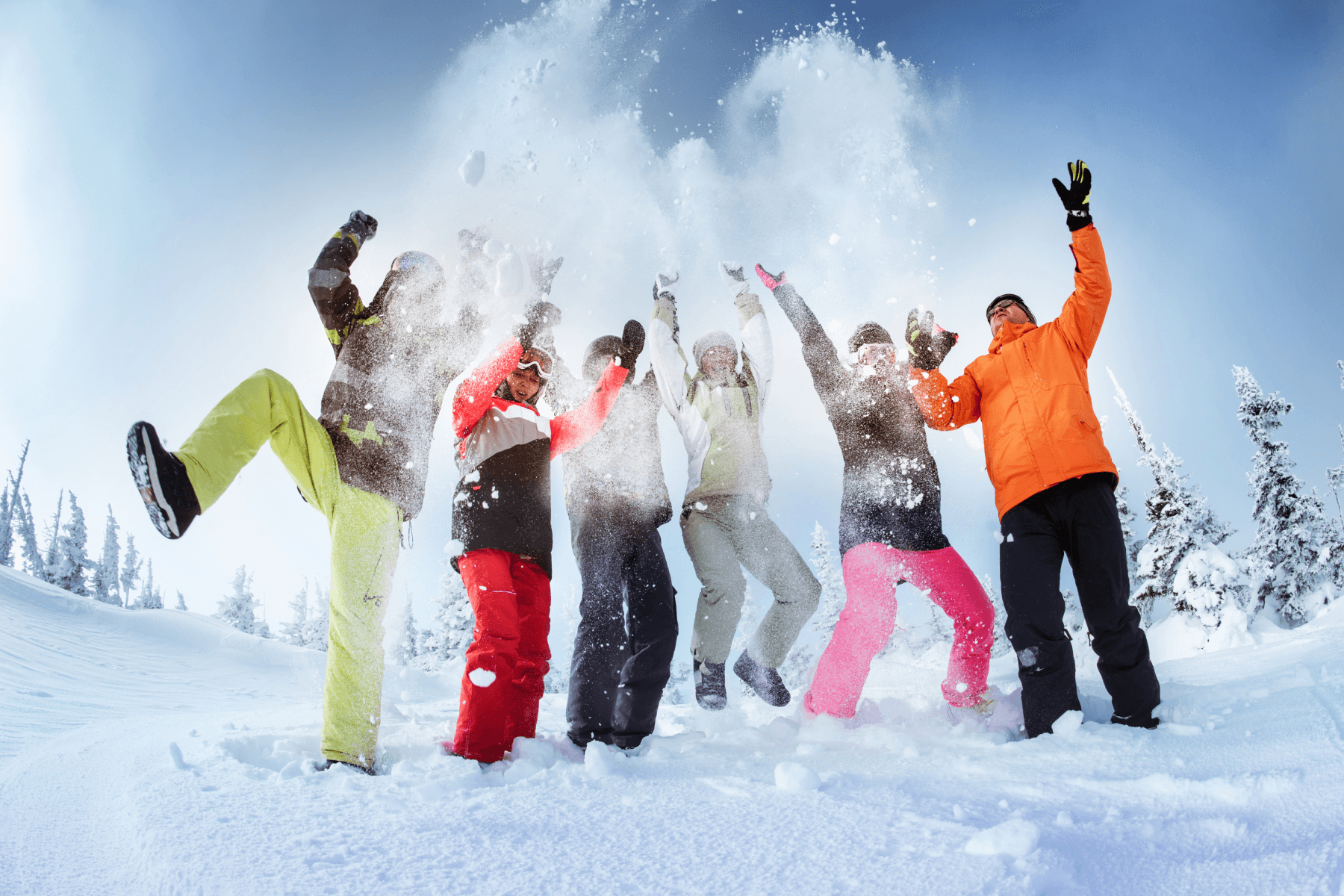 A group of six people in colorful ski gear playing in the snow.