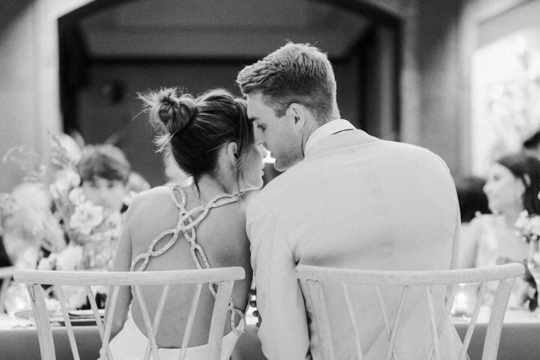 A groom whispers to his bride at a table