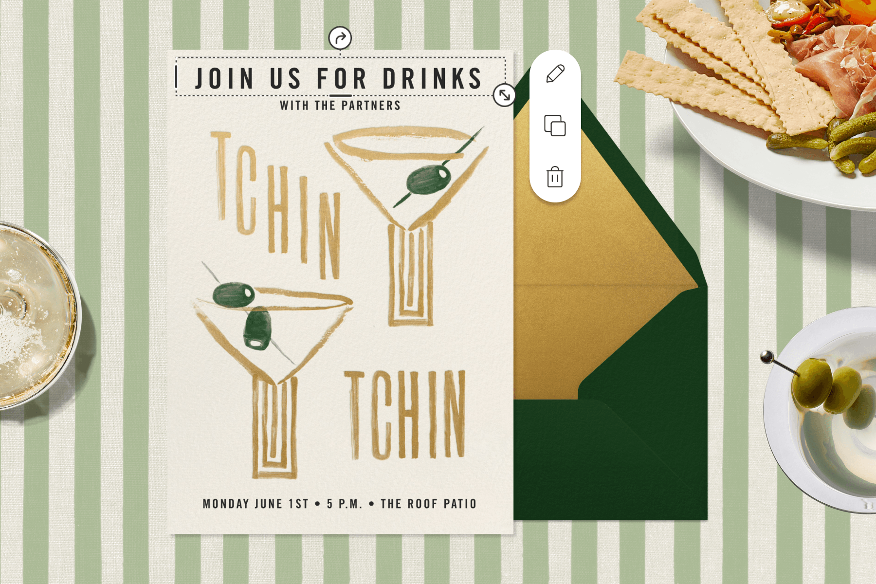 Snacks and drinks sit on a striped green-and-white backdrop designed to look like a table. In the center, a green envelope with gold lining sits beneath a white invitation with black-and-gold lettering. The invitation features two martini glasses with olives and the words ‘Tchin Tchin’.