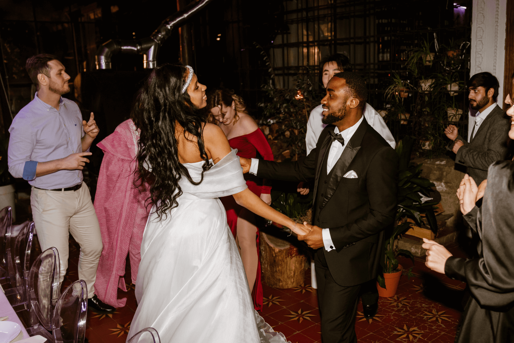A bride, groom, and wedding guests dancing on a dance floor at a wedding.