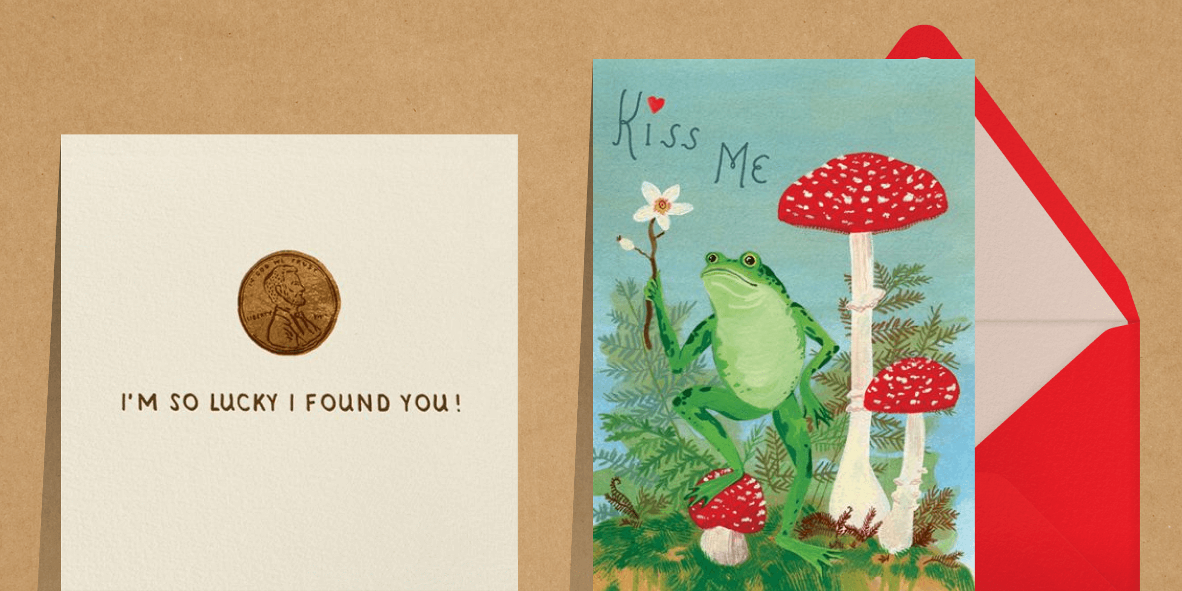 Two side-by-side Valentine’s Day cards. Left - An illustration of a penny with the phrase “I’m so lucky I found you.” Right - An illustration of a frog holding a flower and surrounded by ferns and toadstools with the phrase “Kiss me.” The right card is paired with a red and pink envelope.