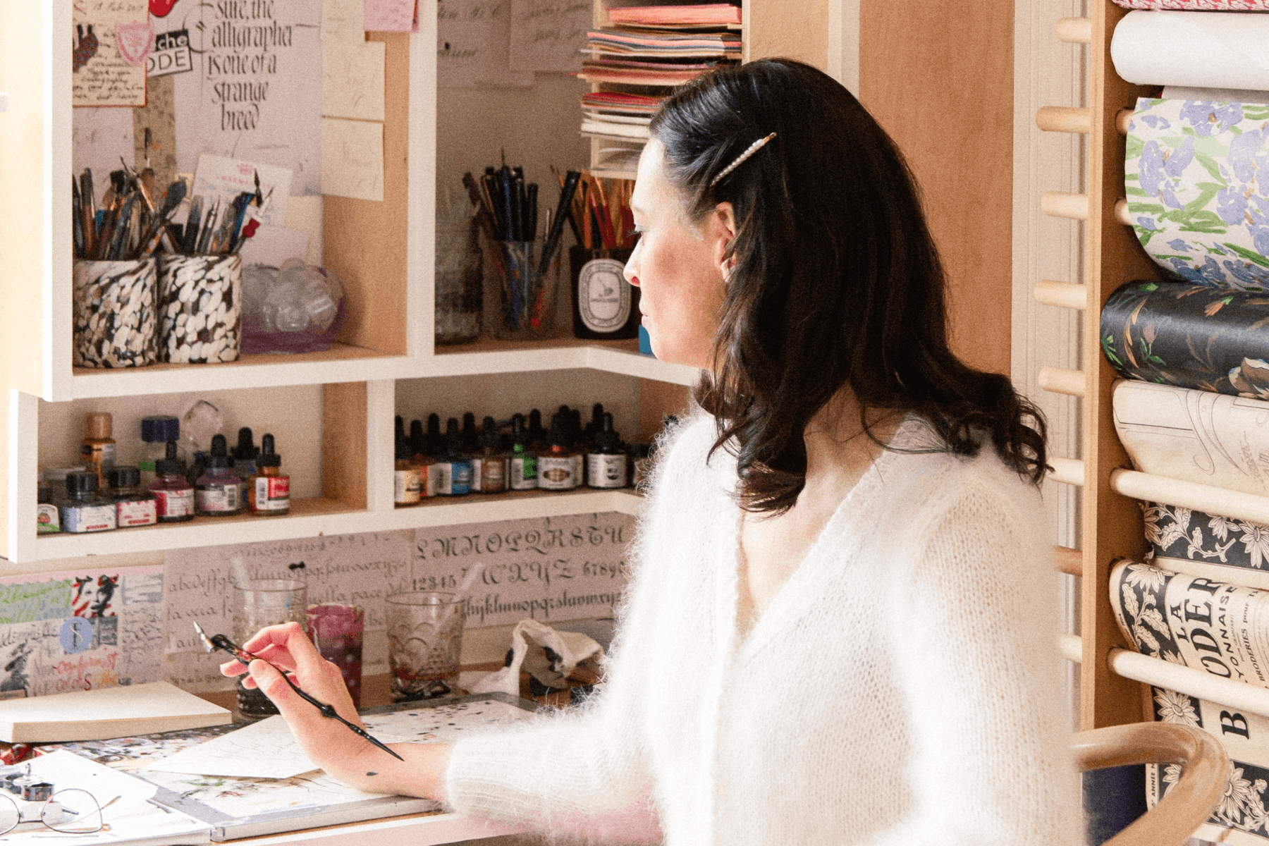 Stephanie Fishwick sitting at her desk with a calligraphy pen in her hand.