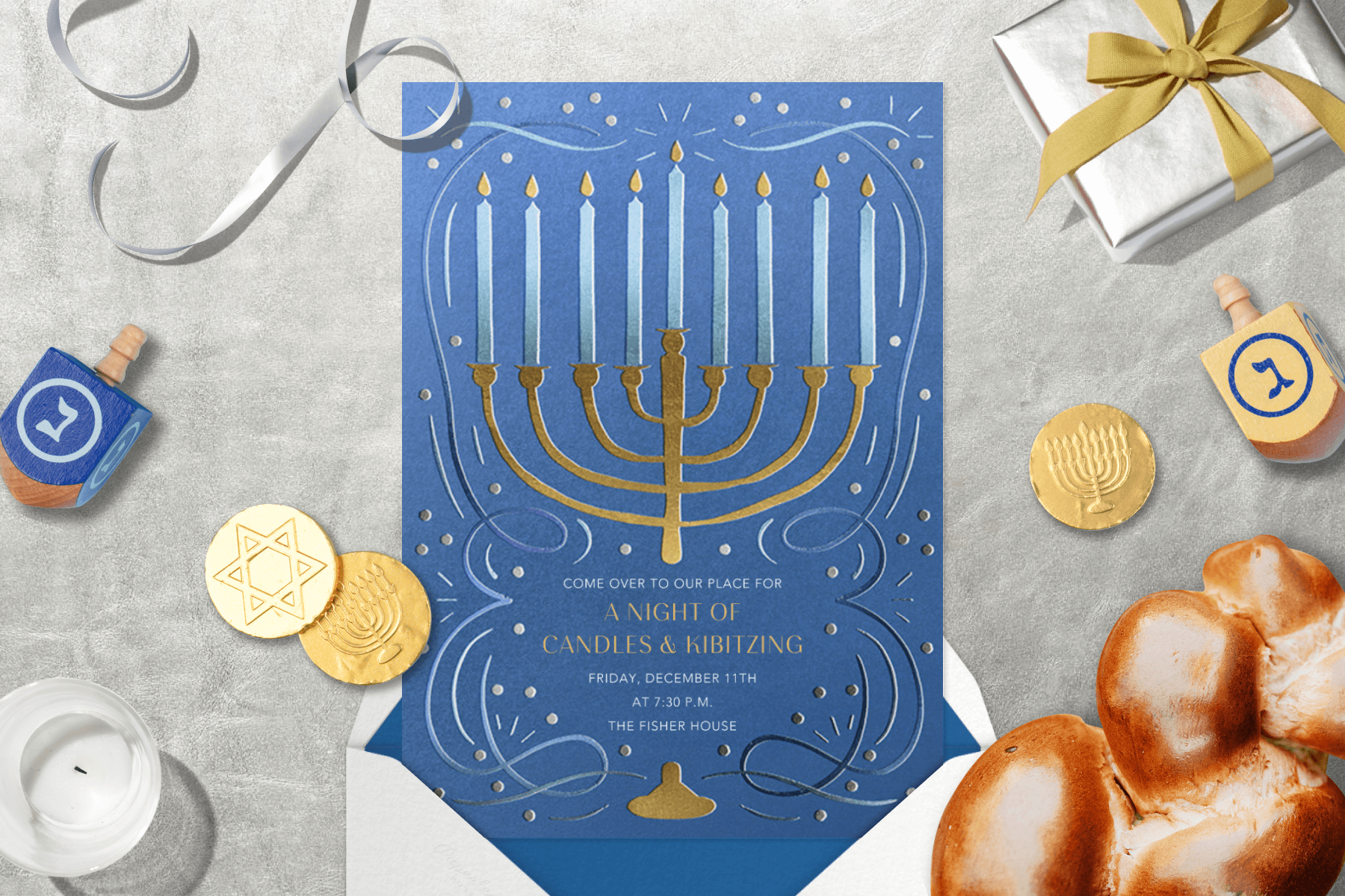 A Hanukkah invitation featuring a gold menorah illustration surrounded by party items like a dreidl, candles, and challah bread.