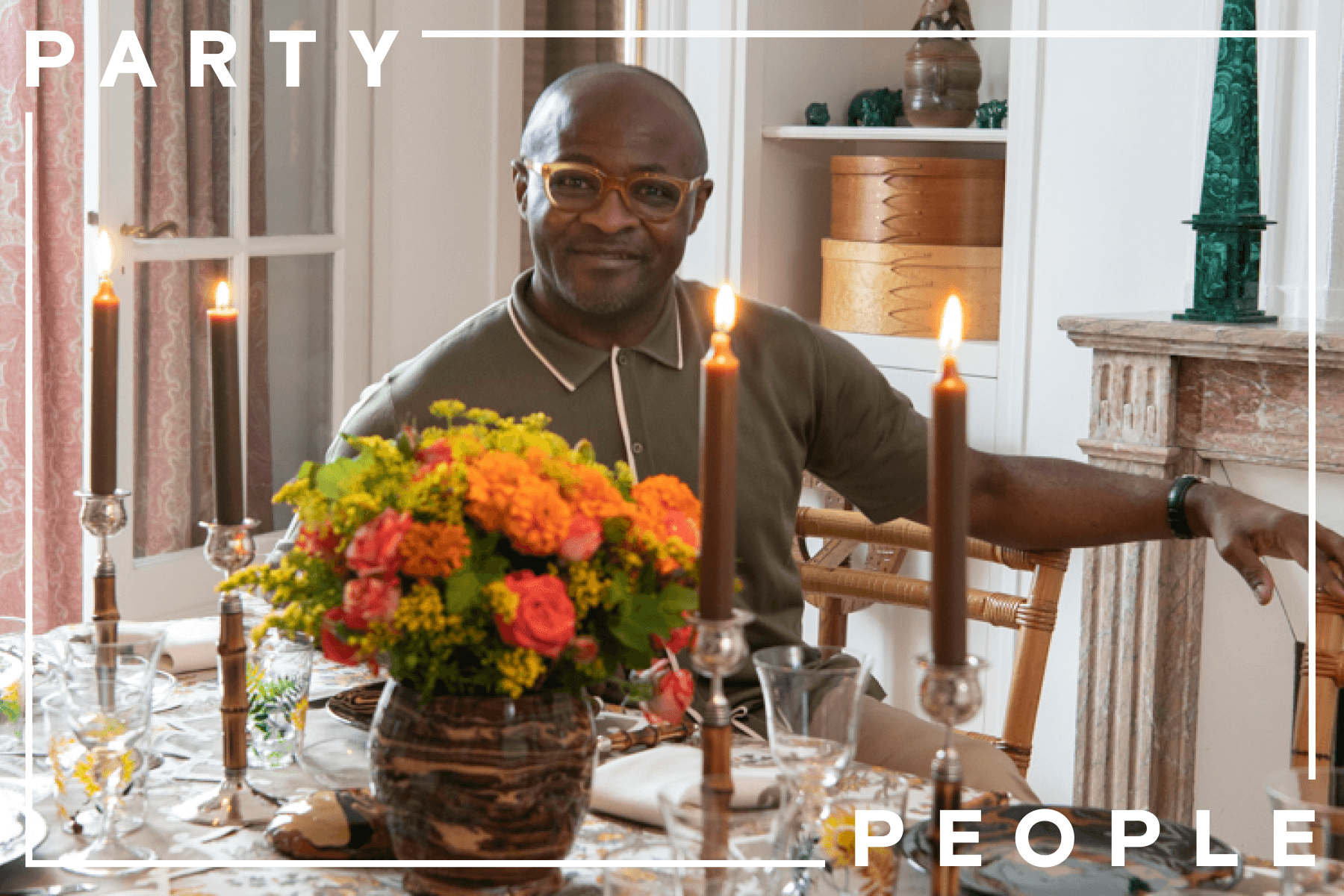 Man, Eric Goujou, sitting at a fall-themed dinner table decorated with orange and yellow flower arrangements and yellow-ochre candles.