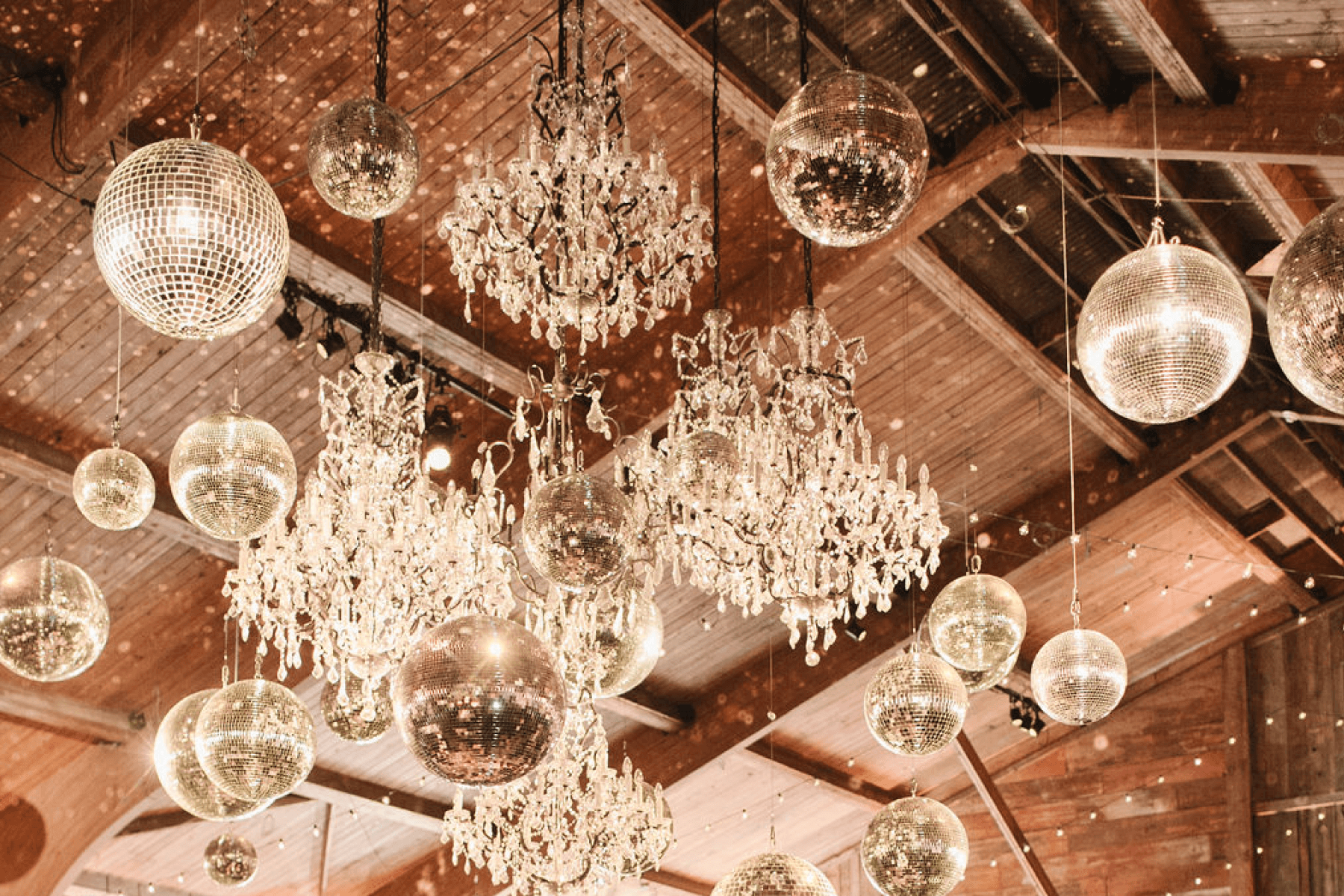 Chandeliers and disco balls hang from a wooden ceiling.