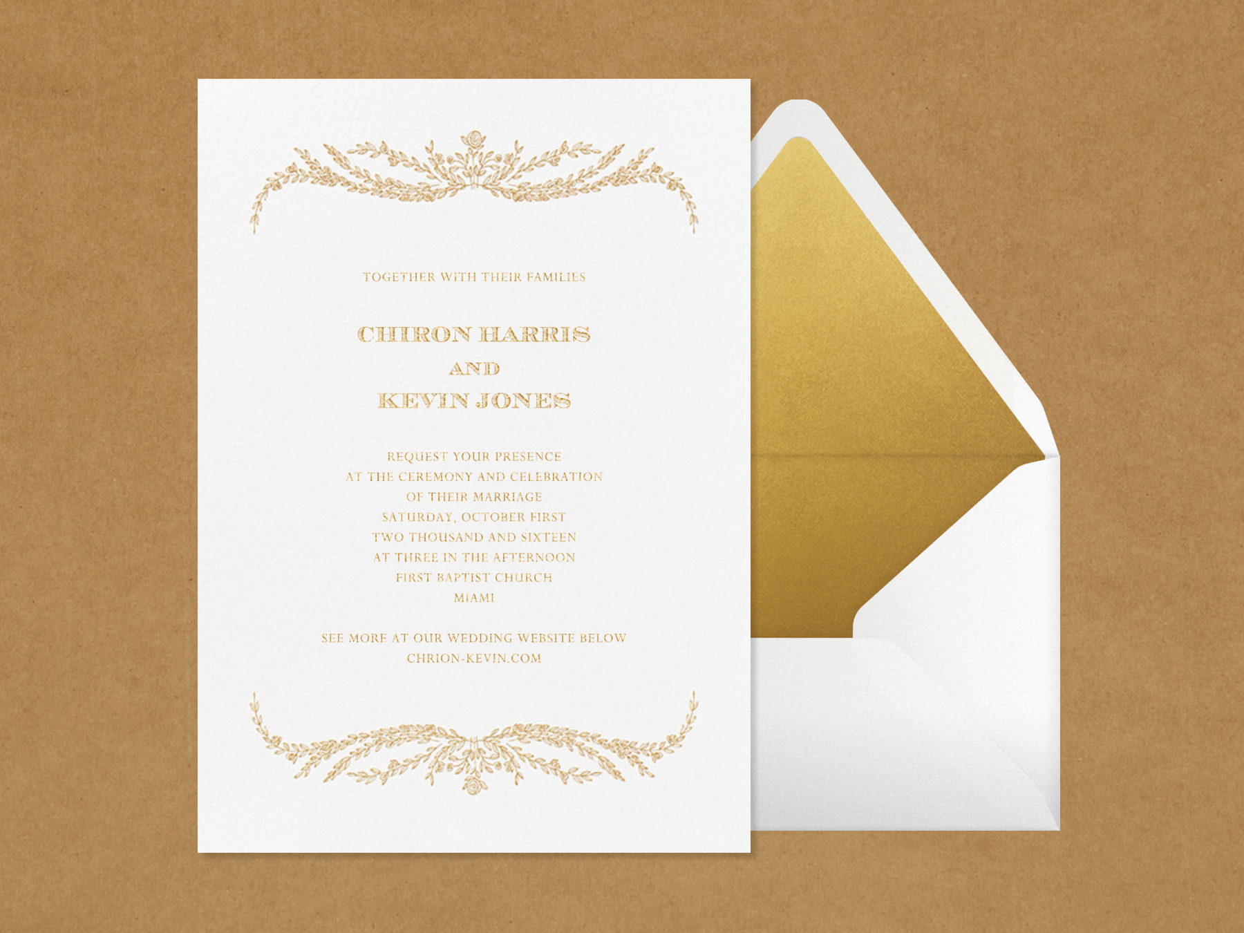 A white wedding invitation with gold leafy flourishes above and below the details next to a white envelope with gold lining on a craft paper background.