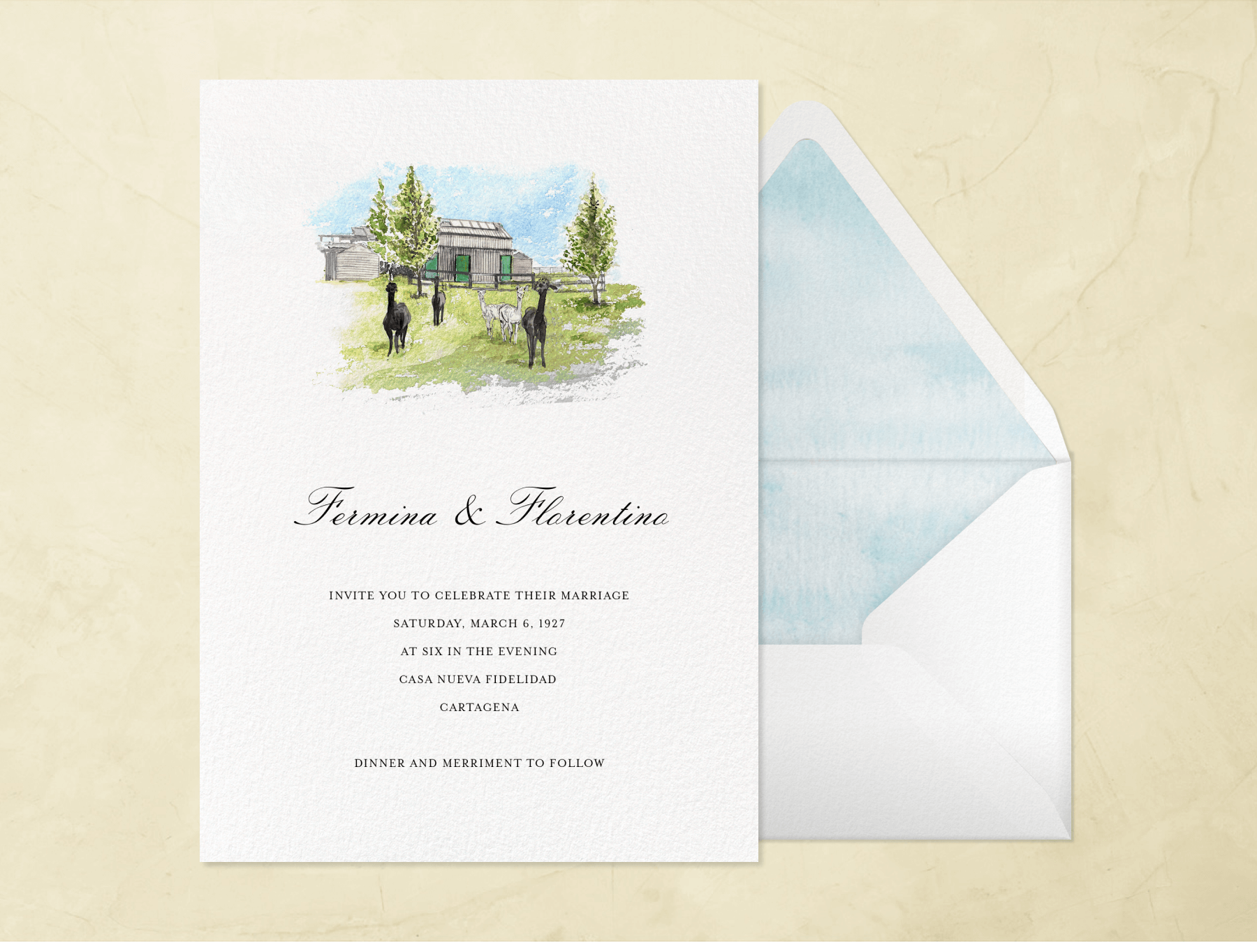 A white wedding invitation with a small watercolor painting of five alpaca in front of a barn beside a white envelope with sky blue watercolor liner on a neutral textured background.