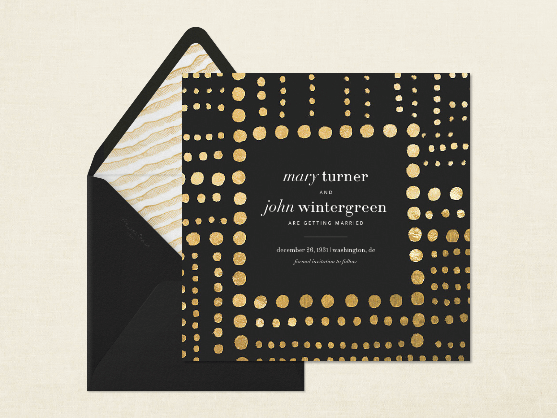 A black wedding invitation with painterly gold dots in various sizes forming a border beside a black envelope with gold zebra stripe liner on a neutral background.