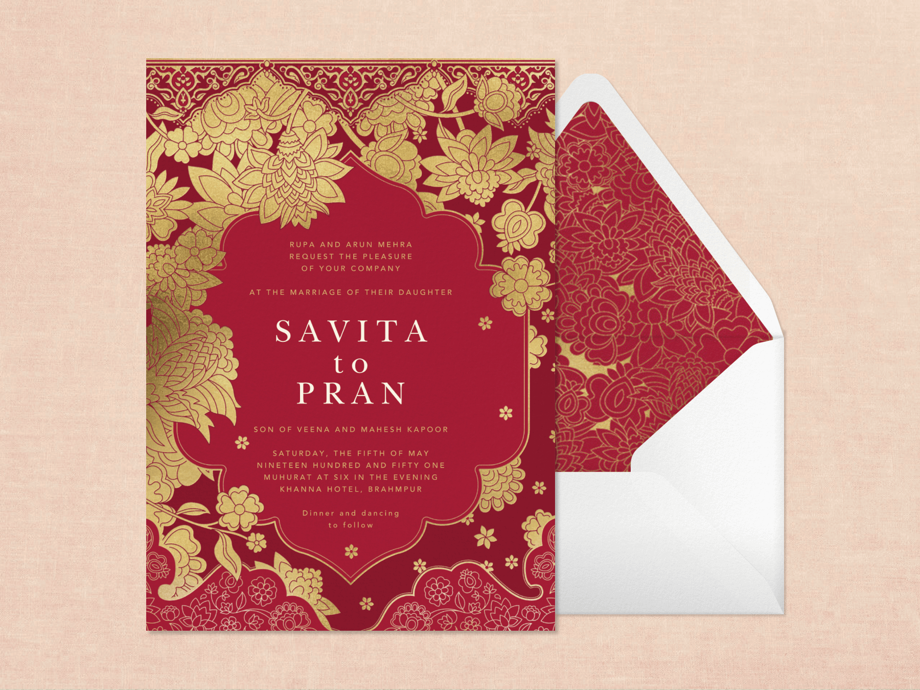A maroon wedding invitation with Indian-style gold arabesque and floral border next to a white envelope with matching liner on a light pink textured background.
