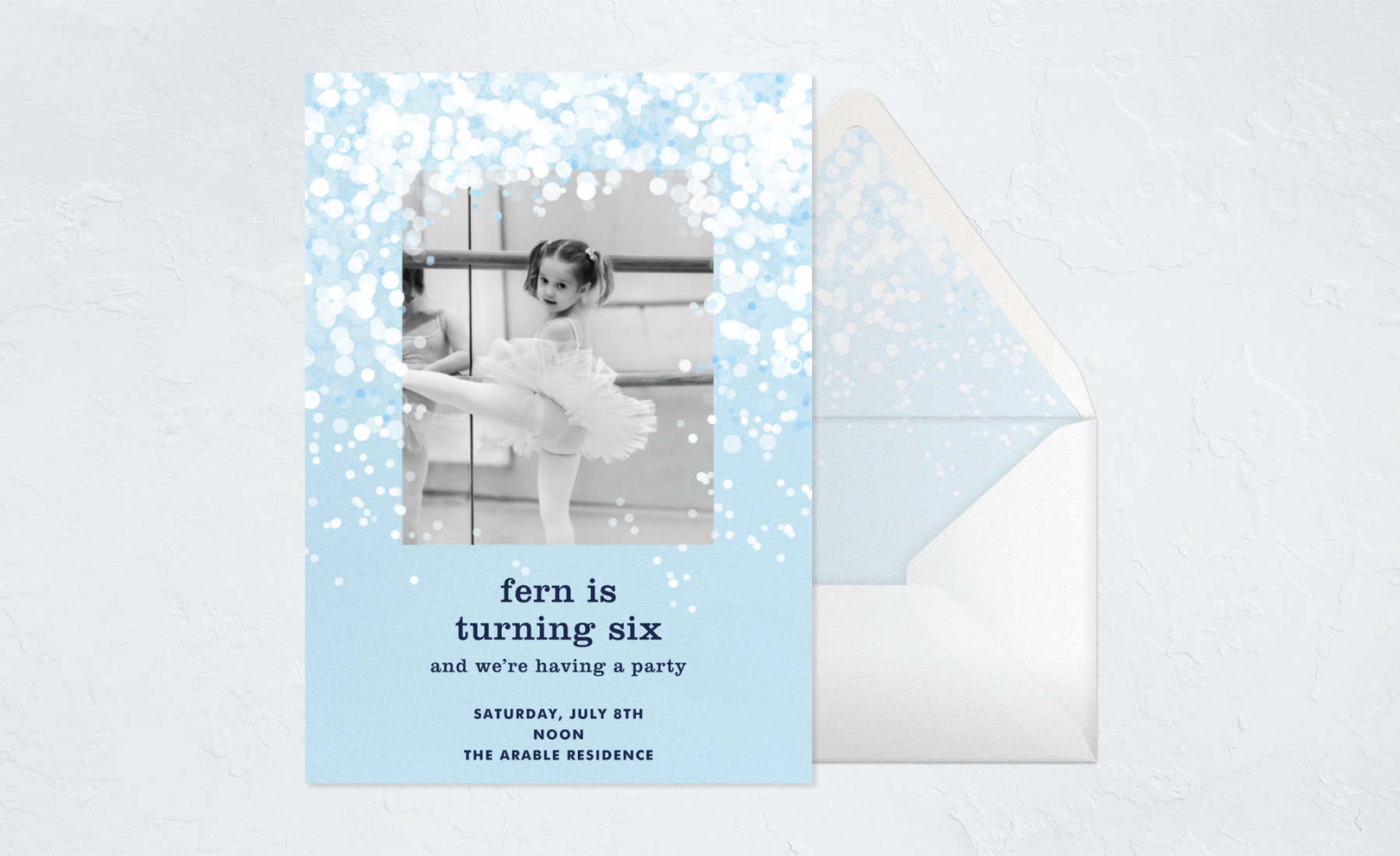 A blue photo card with a flurry of snow around the picture, paired with an envelope.