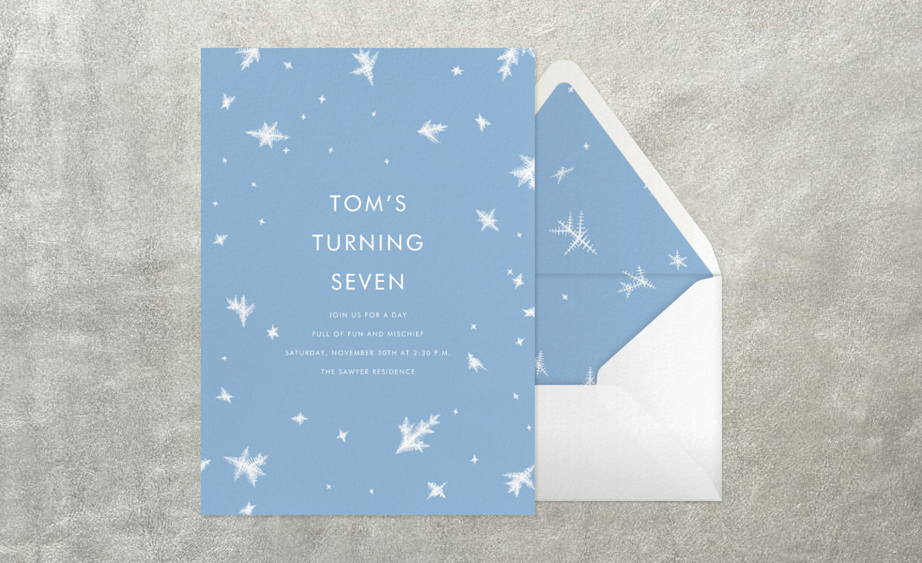 A blue birthday invitation with illustrations of snowflakes, paired with an envelope.
