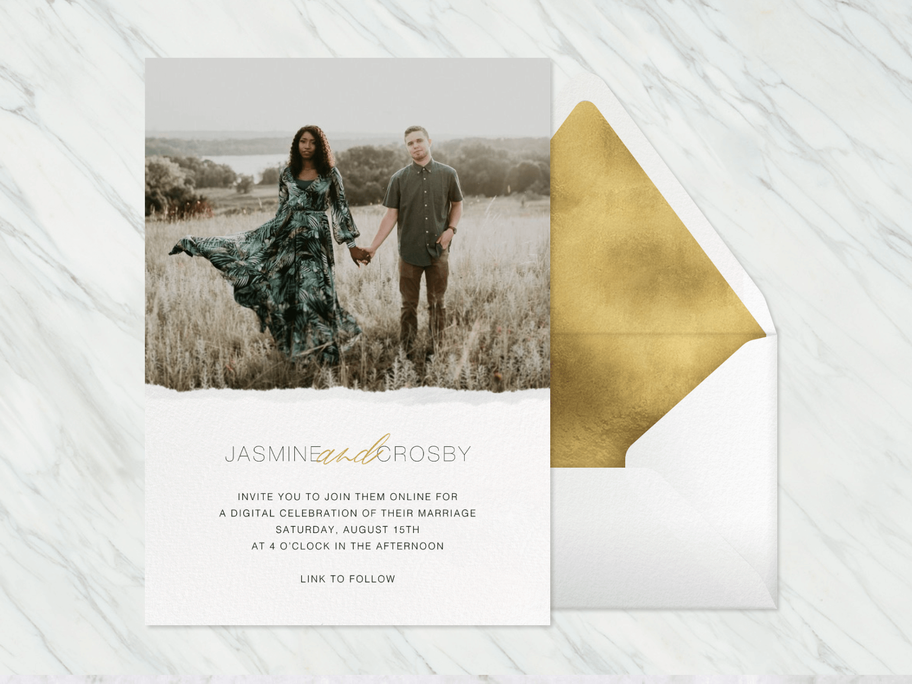 A wedding invitation with a photo of a couple in grasslands on the top and a raw edge look below, beside a white envelope with gold liner.