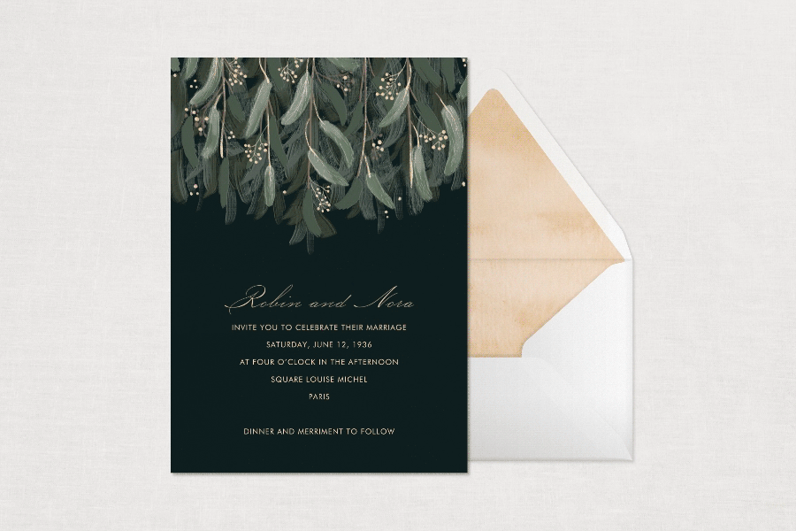 A black wedding invitation with sage green bows of greenery hanging from the top next to an envelope that is flashing between different colors and liner options.