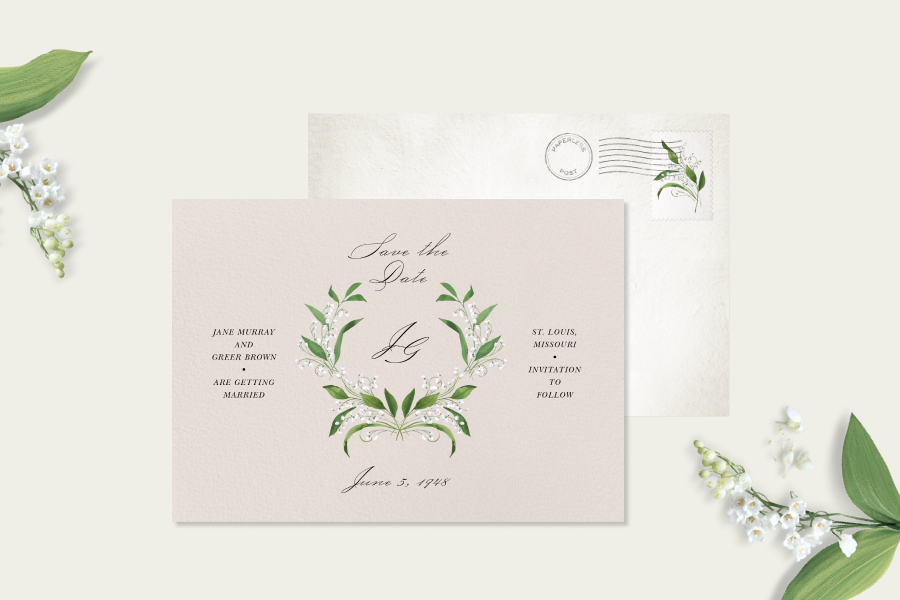 Save the date card featuring a lily of the valley floral crest, paired with an off white envelope and lily of the valley propping. 