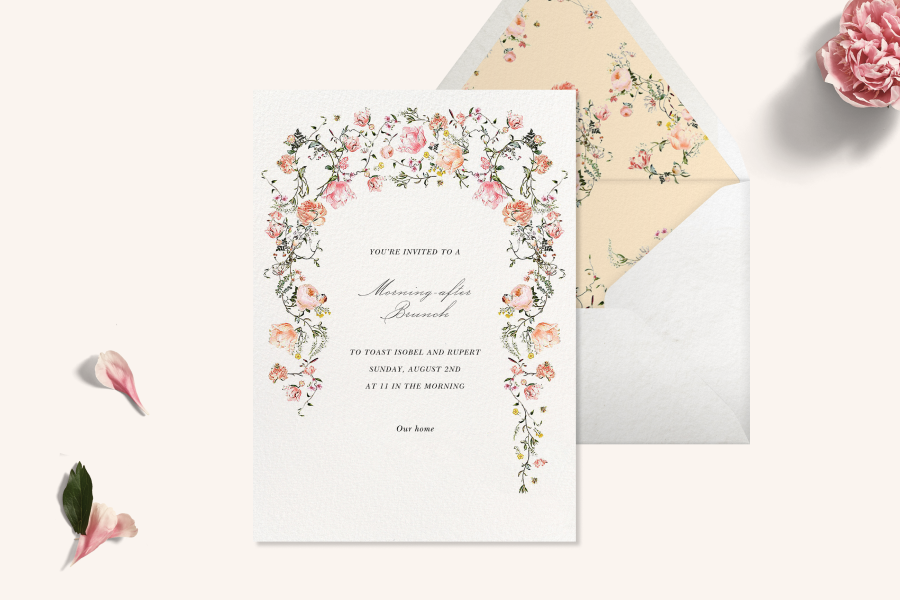 Wedding invitation featuring a white background and a pink and light orange floral arch framing the card, with a white envelope with a floral light orange liner. 