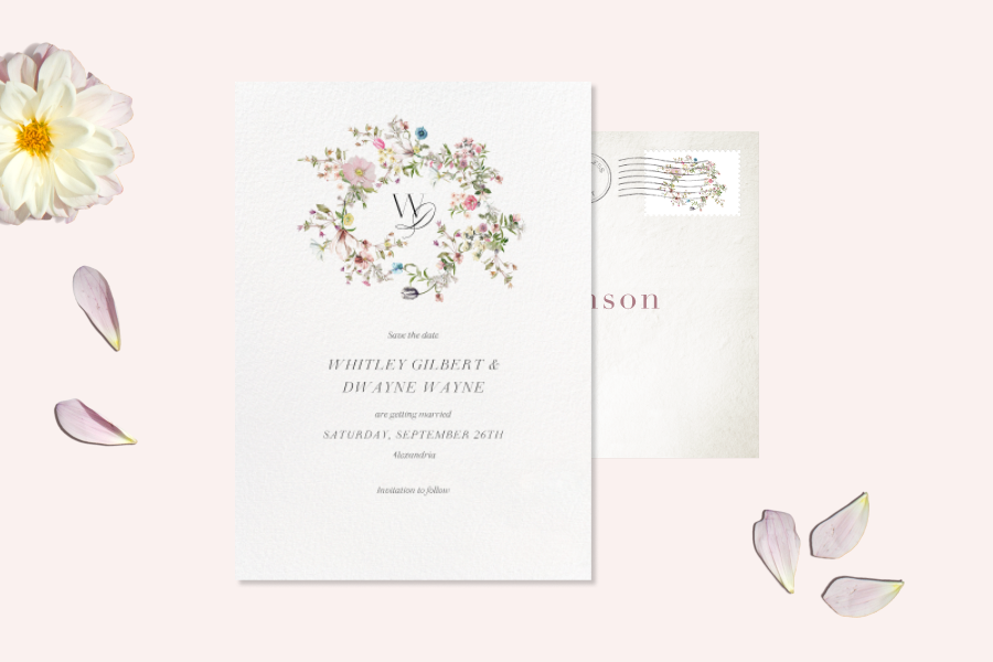 Wedding invitation with a white background featuring a floral crest design in the center of the card. 