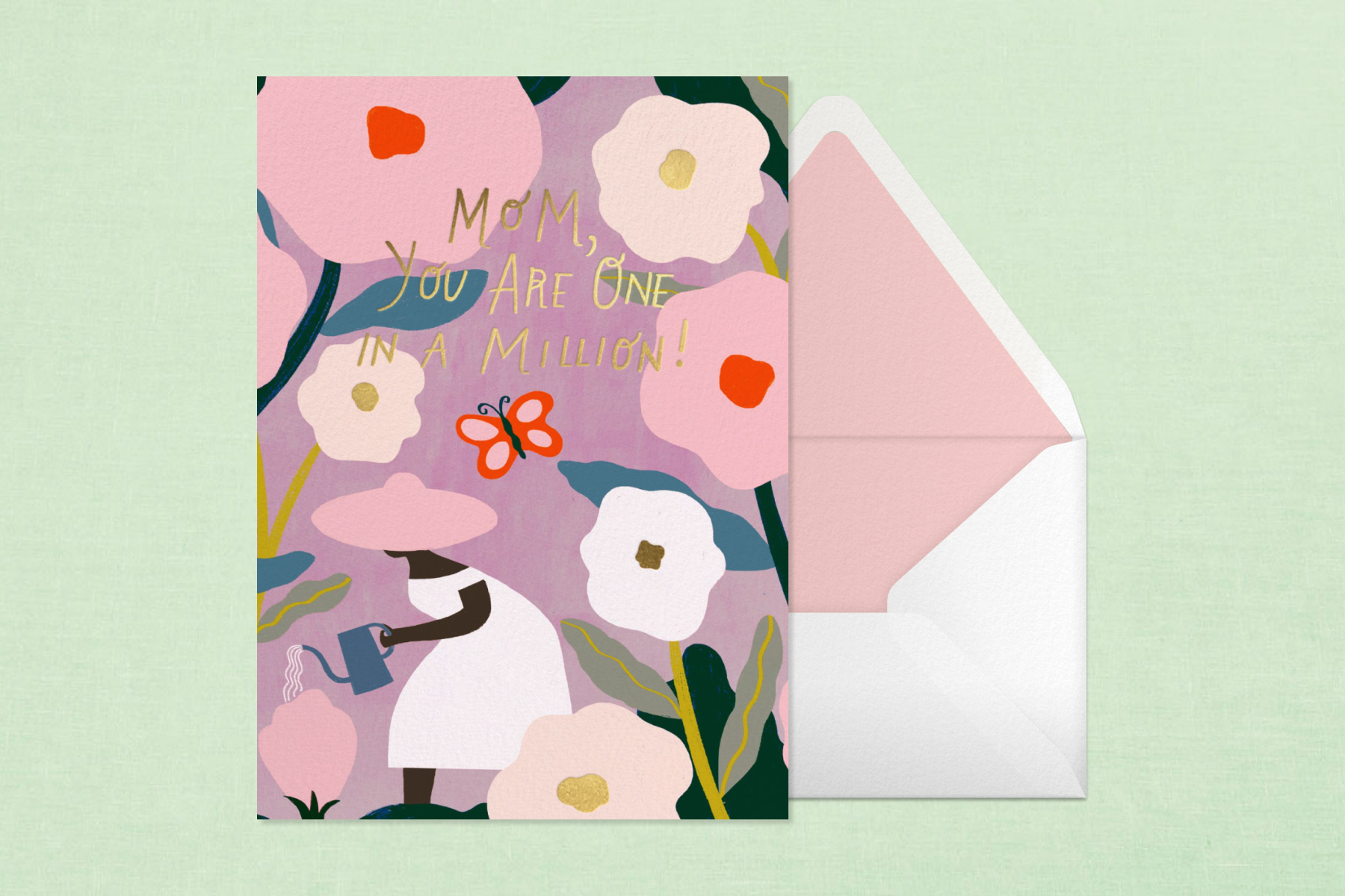 A purple card next to a white envelope with pink trimming reads, ‘Mom, you are one in a million!’ with colorful flowers against a green backdrop.