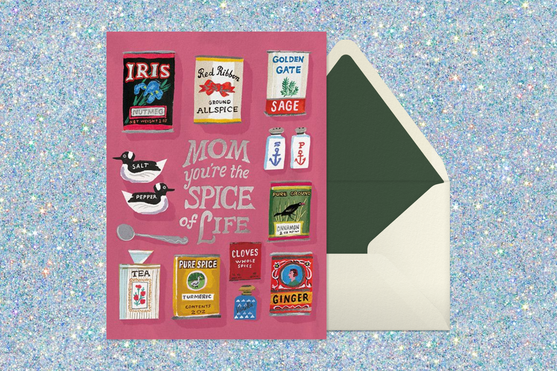 A red card with text that says, ‘Mom, you’re the spice of life’ featuring illustrations of many different kinds of spices next to a white envelope with green trimmings sitting on a sparkly silver backdrop.