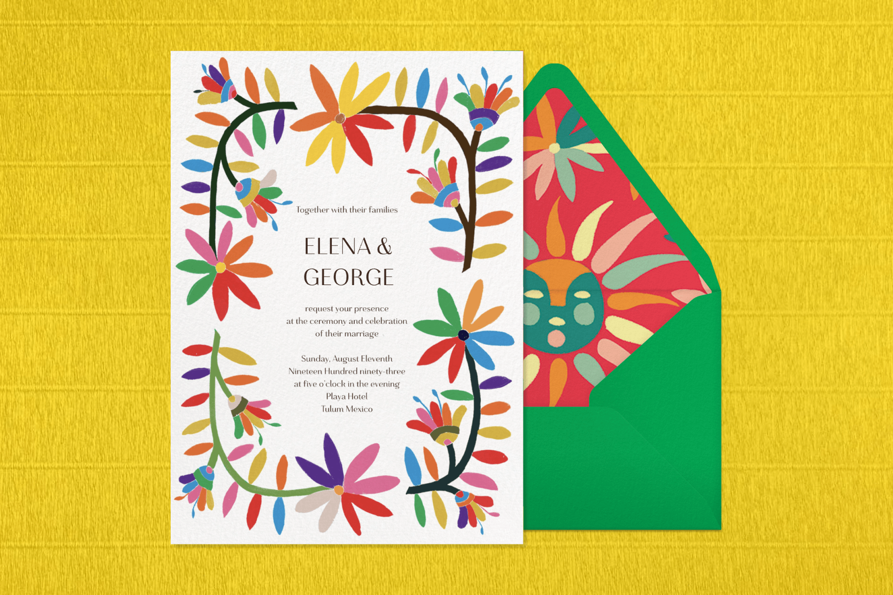 A wedding invitation with a colorful graphic flower border paired with a green envelope, envelope liner with colorful sun and flower graphics, and a woven yellow background.