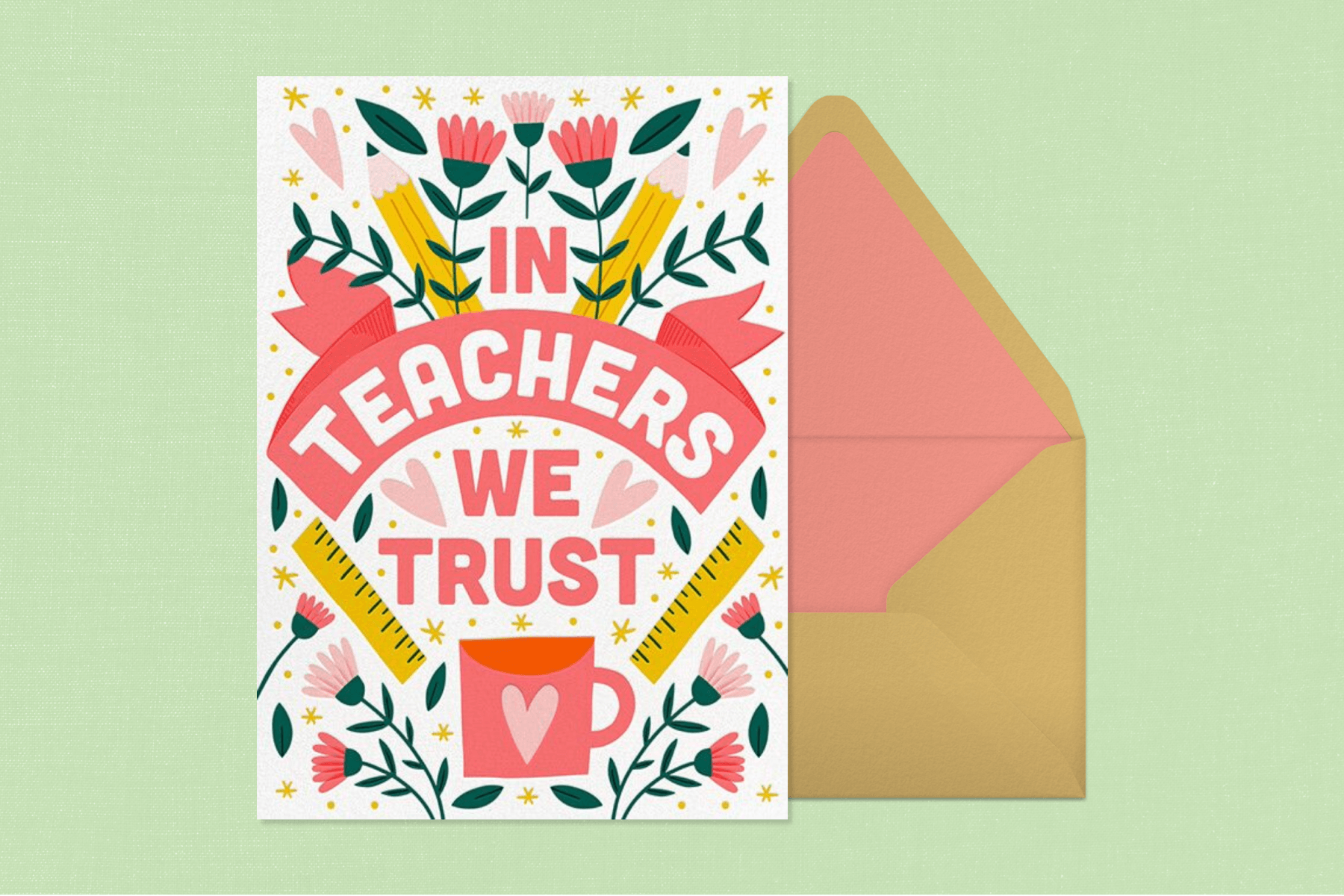 On a mint green backdrop, a white teacher appreciation card with pink flowers, green leaves, yellow rulers, and a pink cup with a heart on it sits on top of a dusty gold envelope with pink lining.