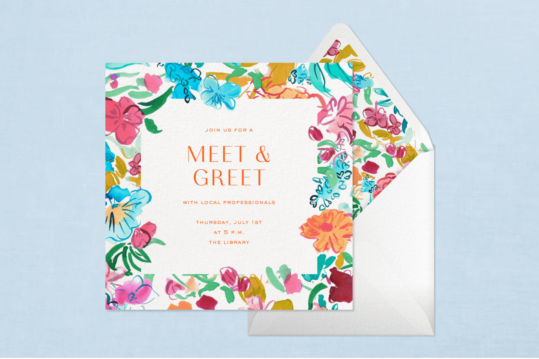 A white square invitation with multicolor, bright floral edges atop a white envelope with a matching liner pattern, all laid on a light blue background.