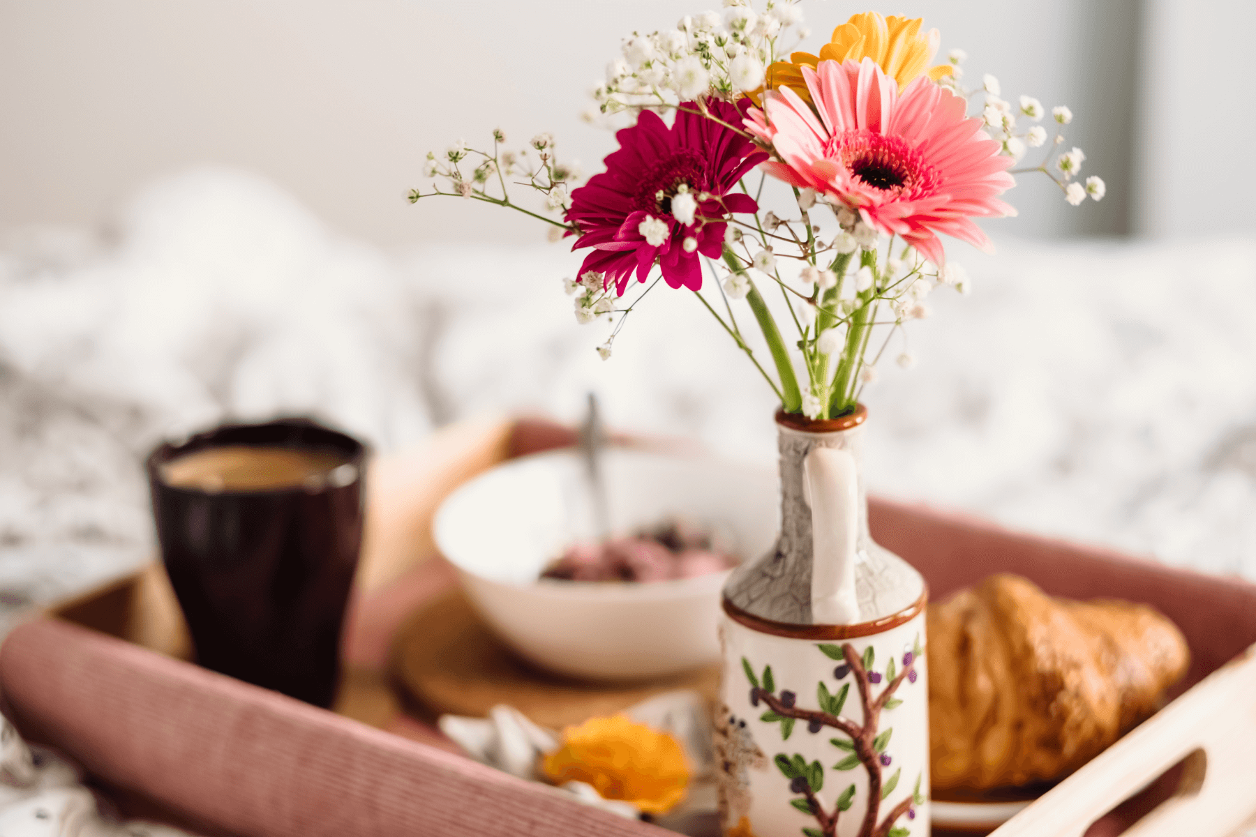 A soft focus photo of breakfast in bed with flowers.