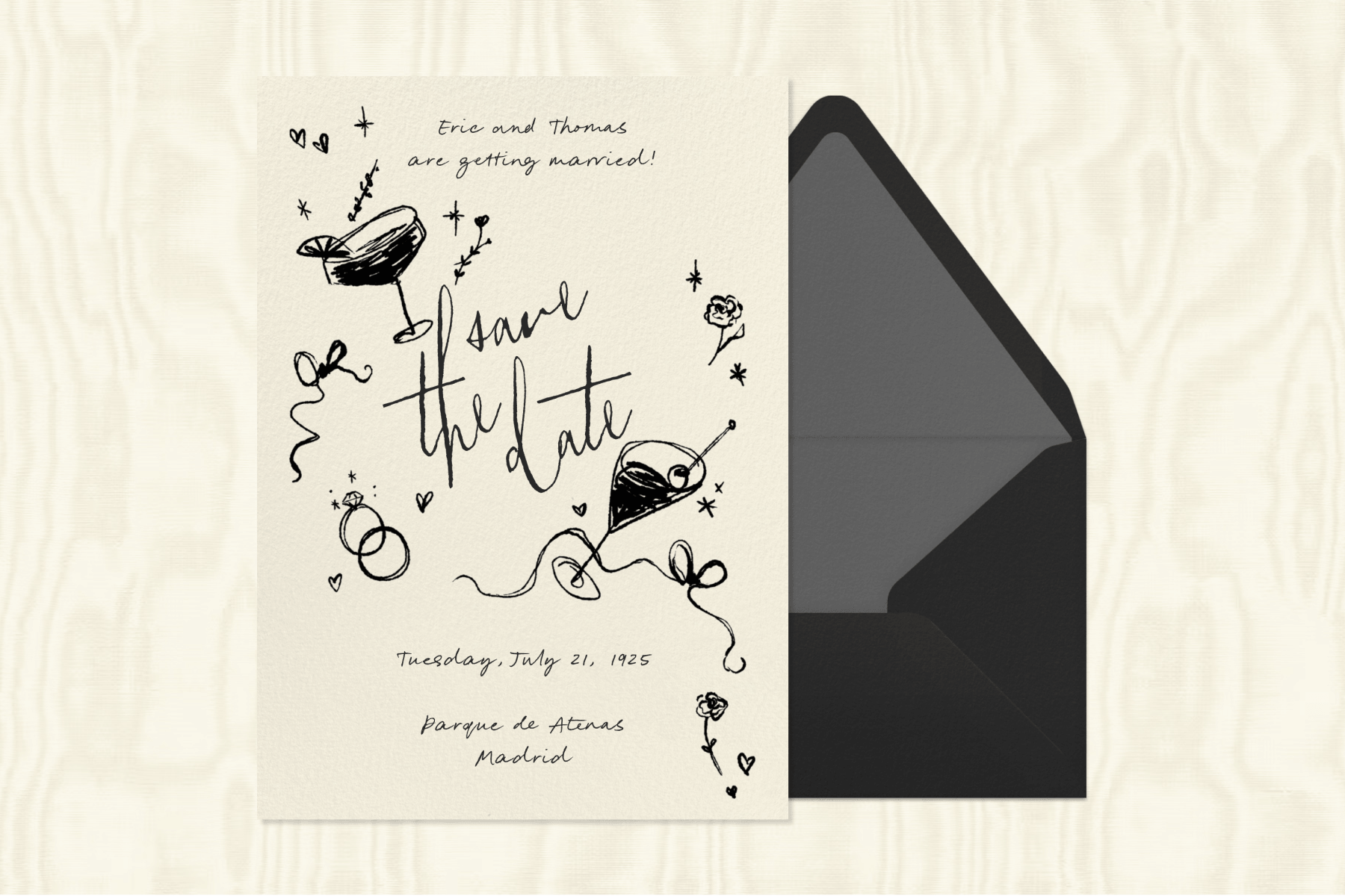 A hand-drawn save the date invitation with illustrations of martinis, rings, flowers, and ribbons next to a black envelope with a gray interior, against a cream-colored textured background.