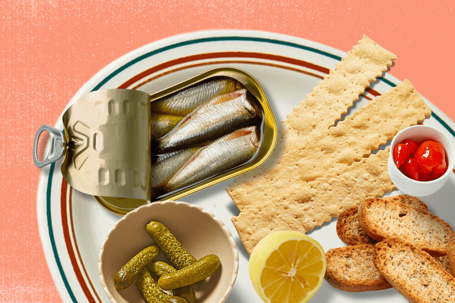 A fish board with tinned fish, long crackers, crostinis, cornichons, tomatoes, and a lemon sit atop an ivory plate with red and green stripes against a textured light terracotta backdrop.
