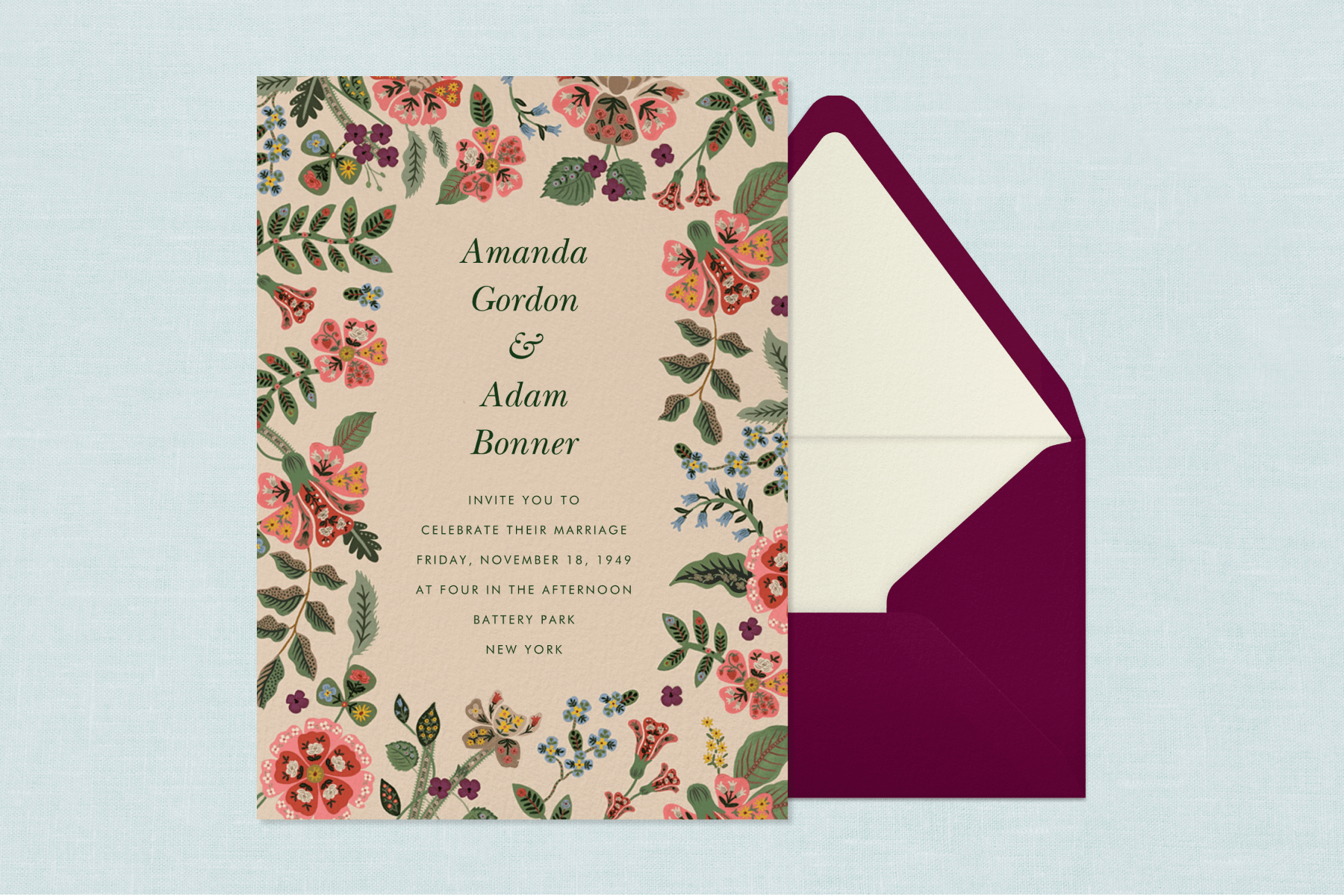 A wedding invitation featuring a colorful floral illustrated border paired with a burgundy envelope, cream envelope liner, and blue background.