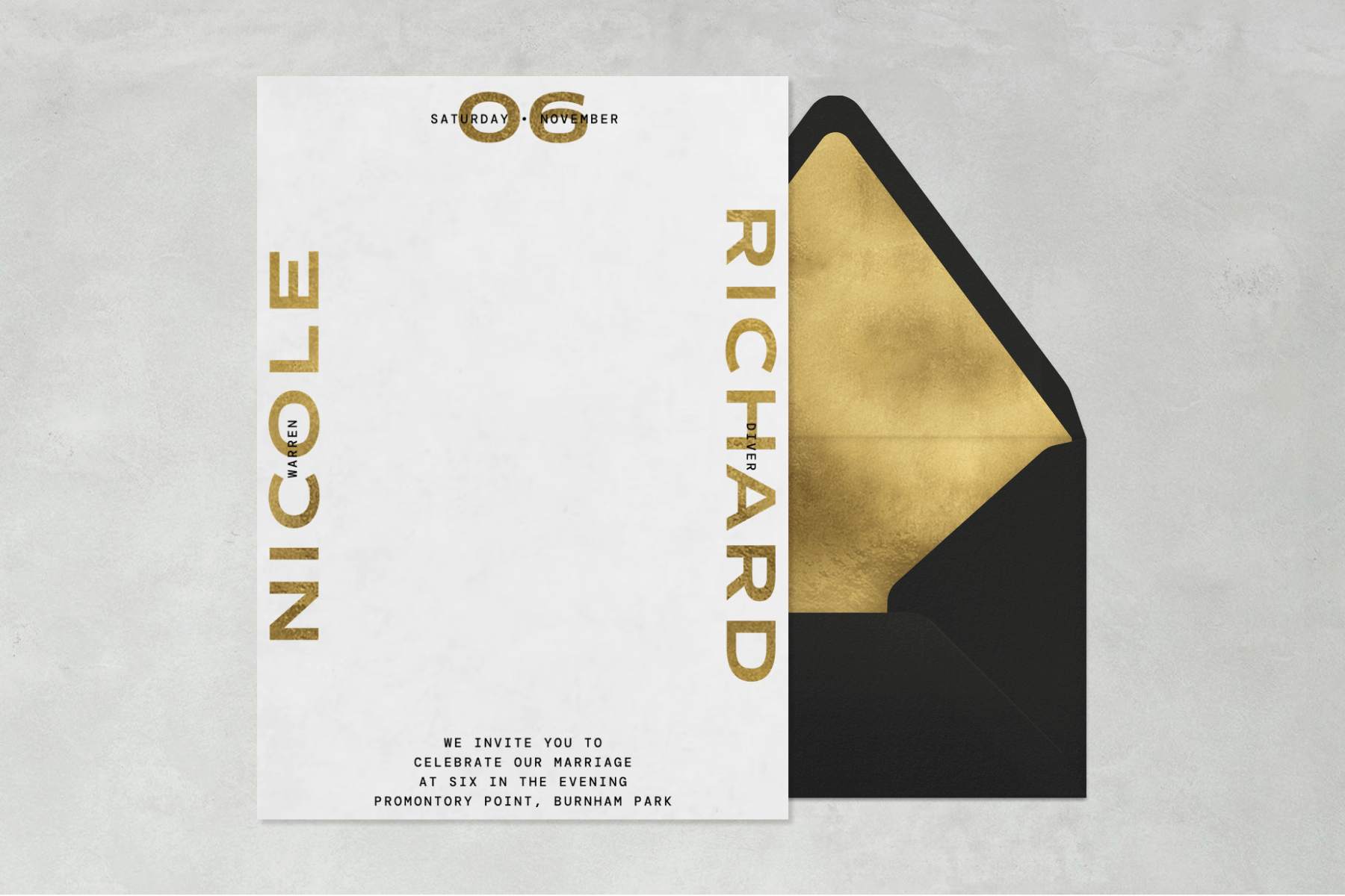 A wedding invitation with a white background and gold block font paired with a black envelope, gold envelope liner, and gray textured background.