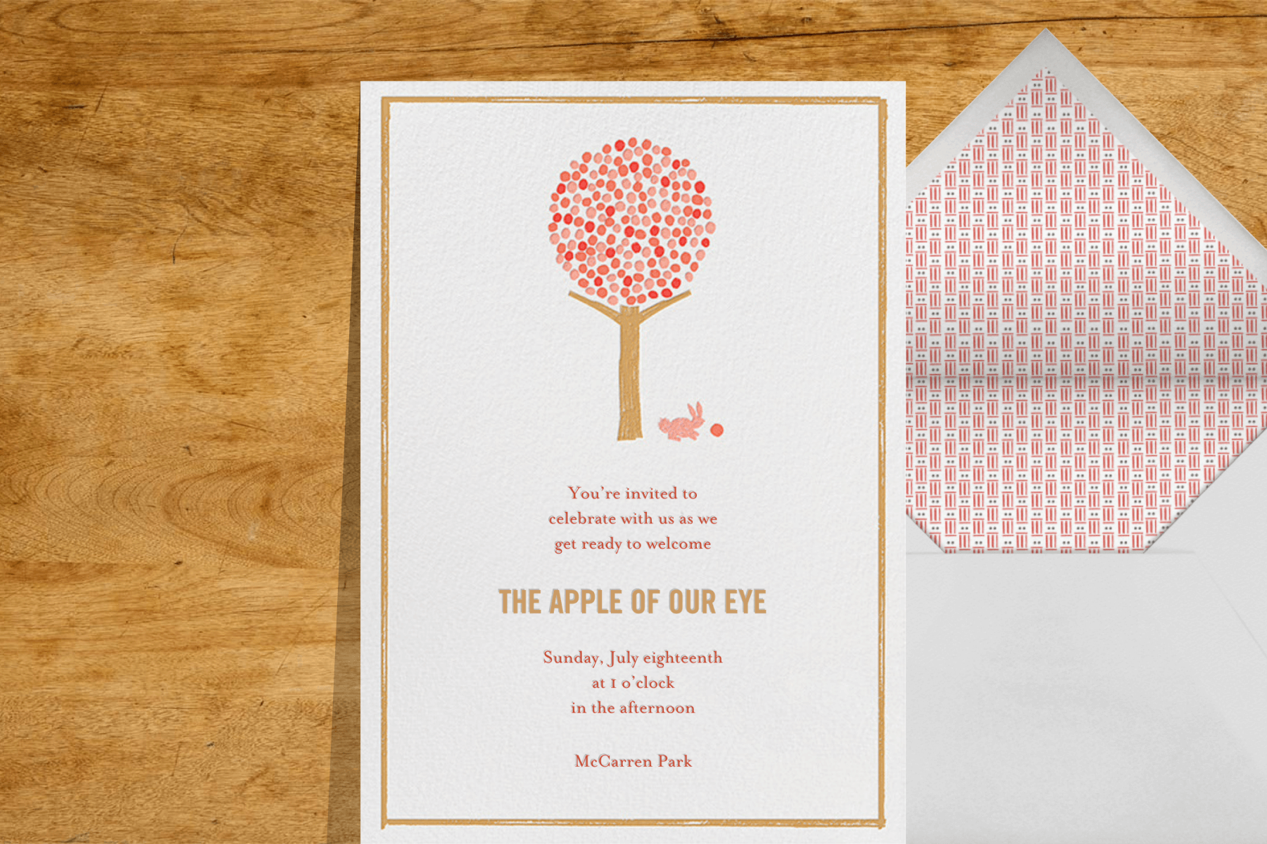 A baby shower invitation featuring an apple tree and a bunny eating an apple.