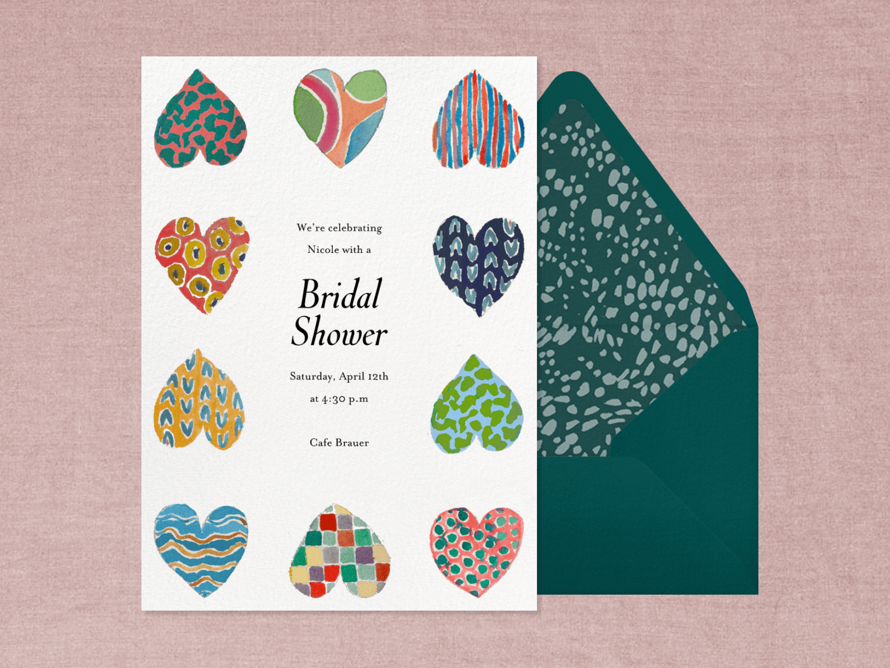 A bridal shower invitation with a border of 10 colorful, multi-patterned hearts in varying positions beside a forest green envelope on a pink textured background.