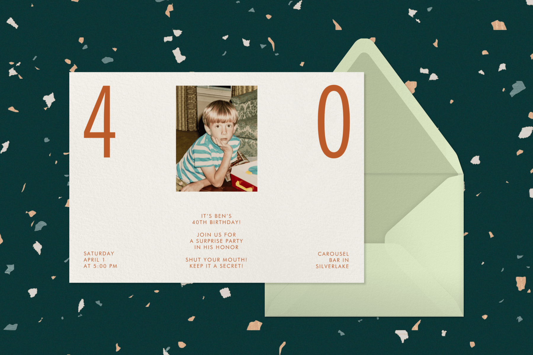 A 40th birthday party invitation with a cream background, orange text, a photo of a young boy, and text that reads ‘40’ paired with a mint green envelope and envelope liner on a dark green background with pastel confetti.