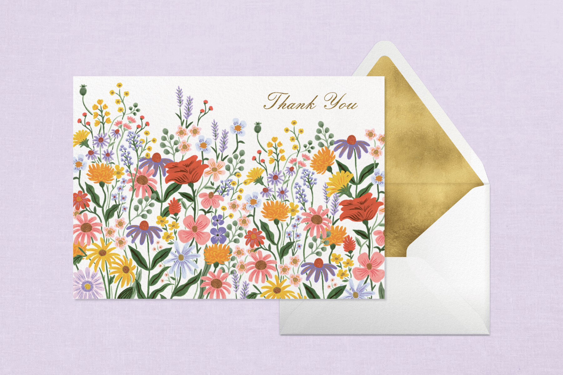 A thank you card featuring colorful flowers and gold cursive text in front of a white envelope with a gold liner.