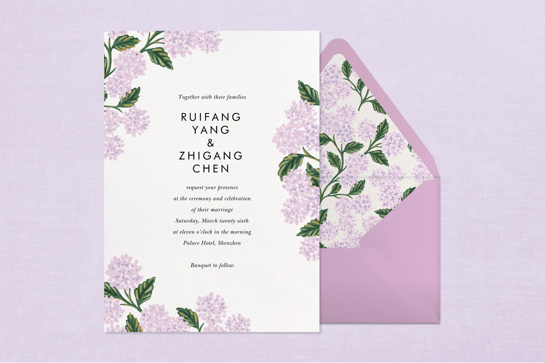 A purple floral wedding invitation sits to the left of a pink envelope with the same floral motif on the interior against a textured light purple backdrop.
