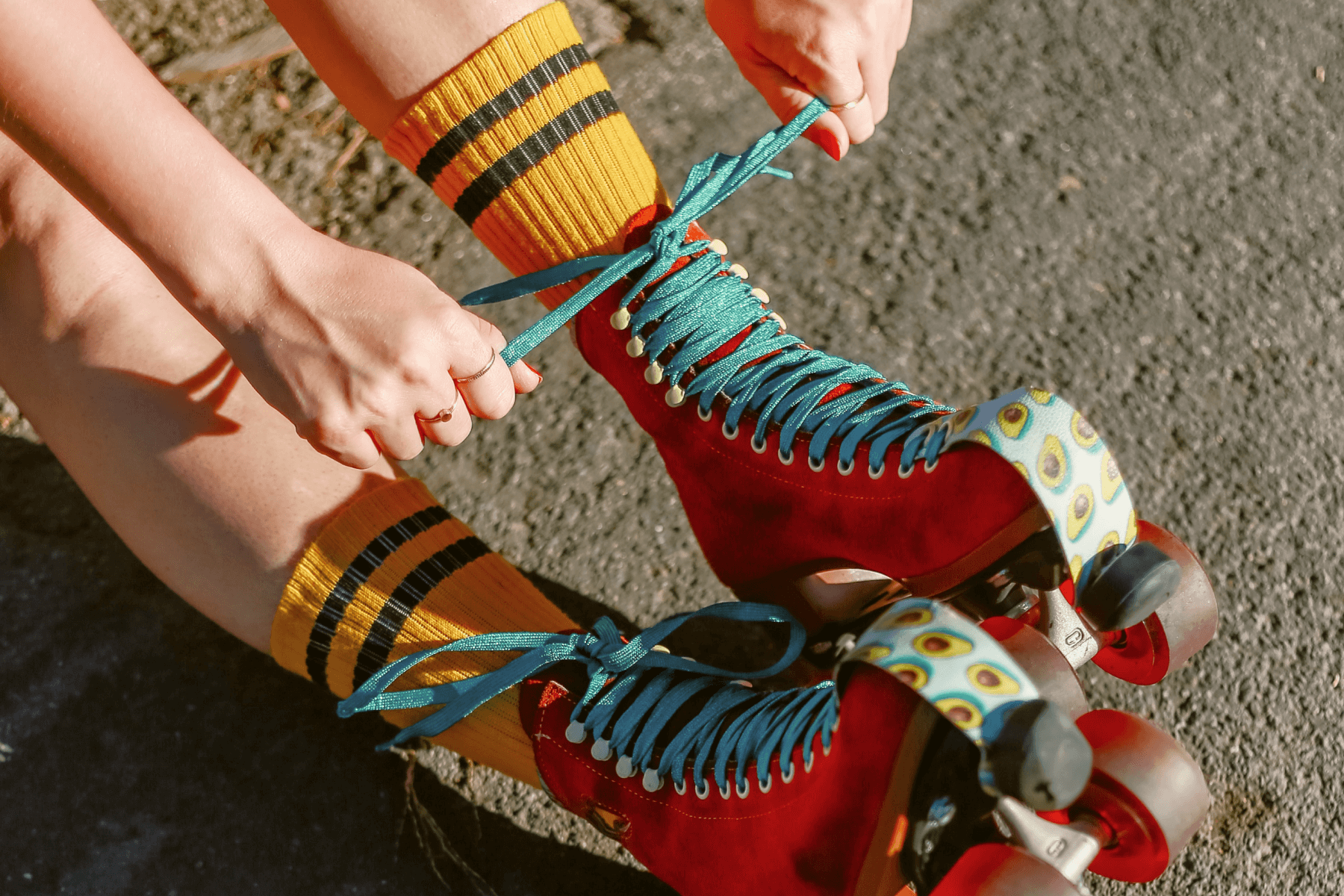 A person laces up red retro rollerskates.