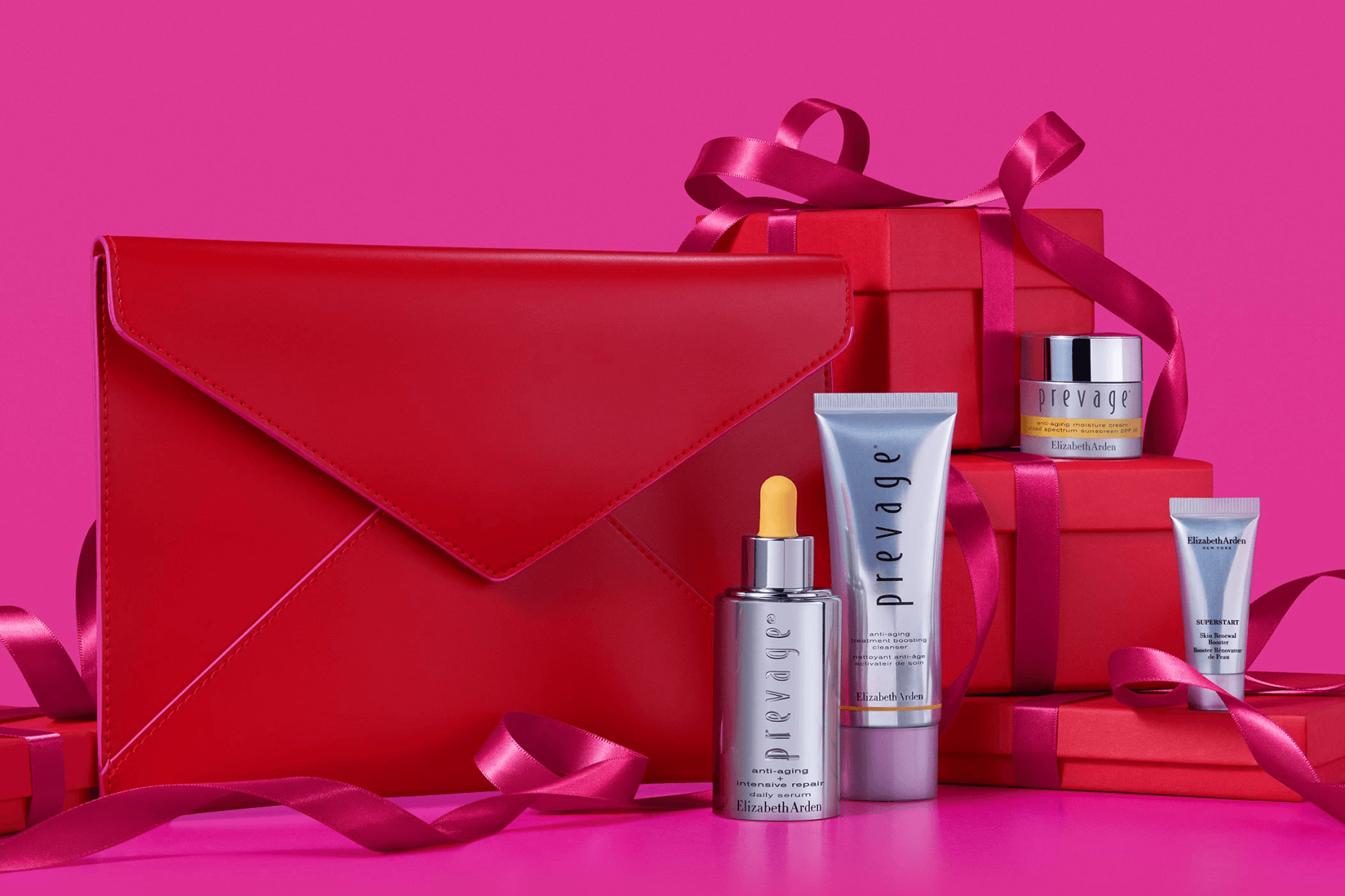 A red gift with purchase bundle of several skincare products on a pink background.