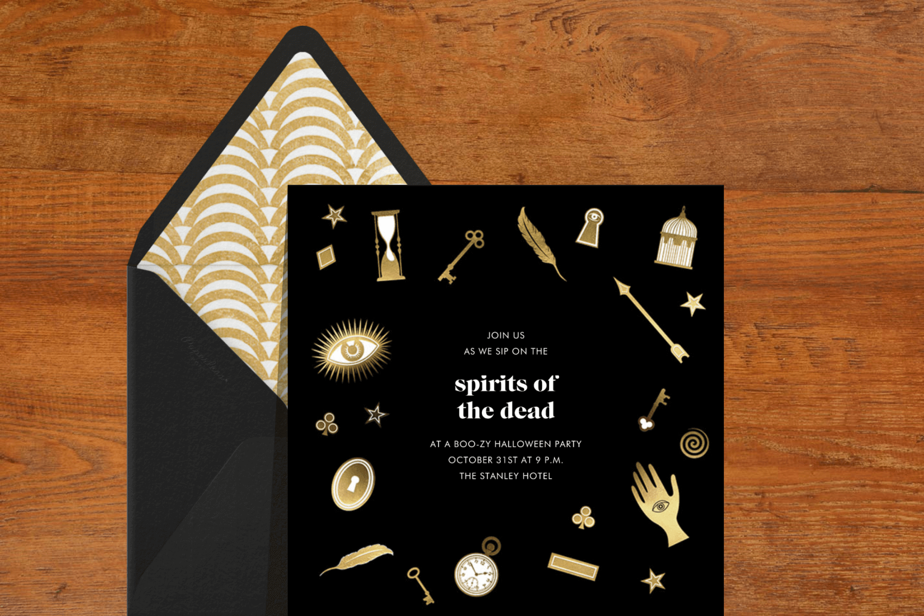 A black invitation with mystical gold items around the border, including third eyes, skeleton keys, feathers, and pocket watches.
