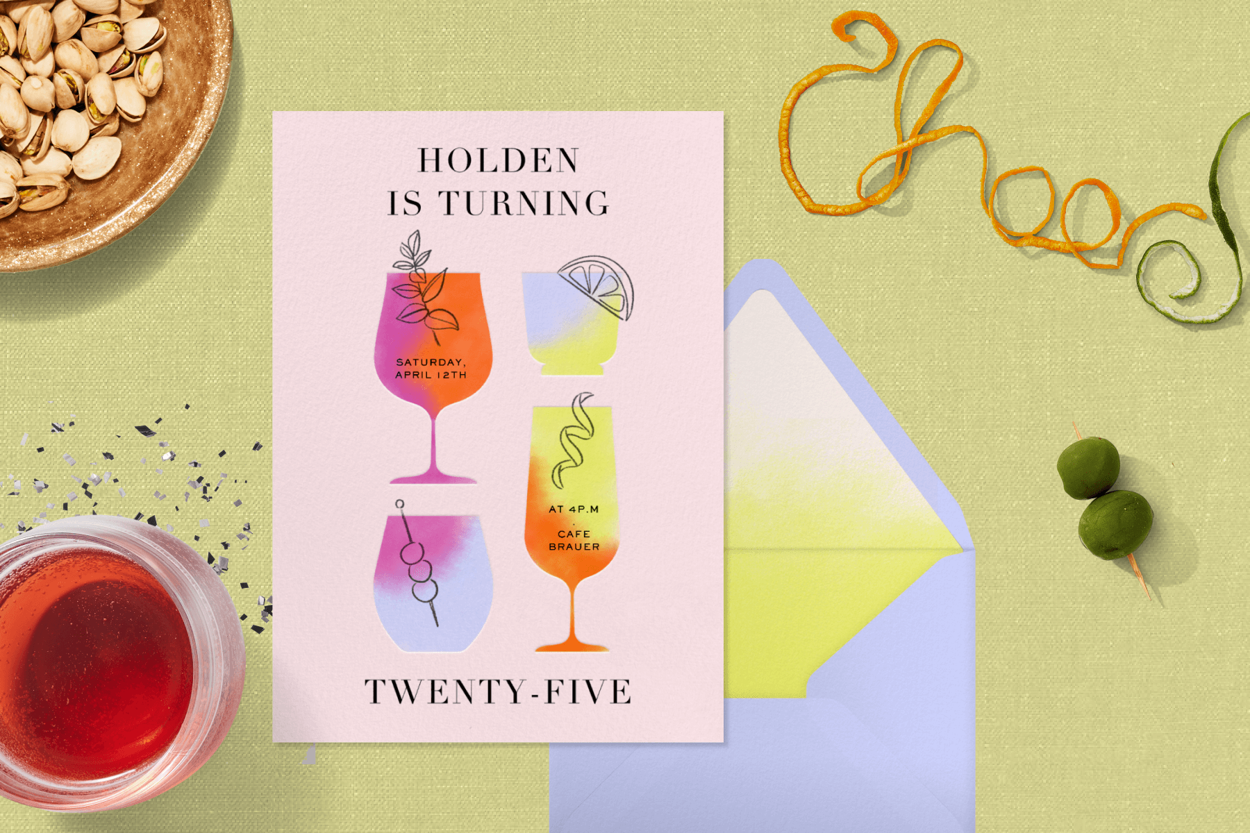 An 25th birthday invitation with illustrations of 4 neon drink glasses rests with a lavender envelope on a pea-green backdrop surrounded by a red drink, glitter, a bowl of pistachios, olives on a skewer, and orange peels configured to spell out “cheers.”