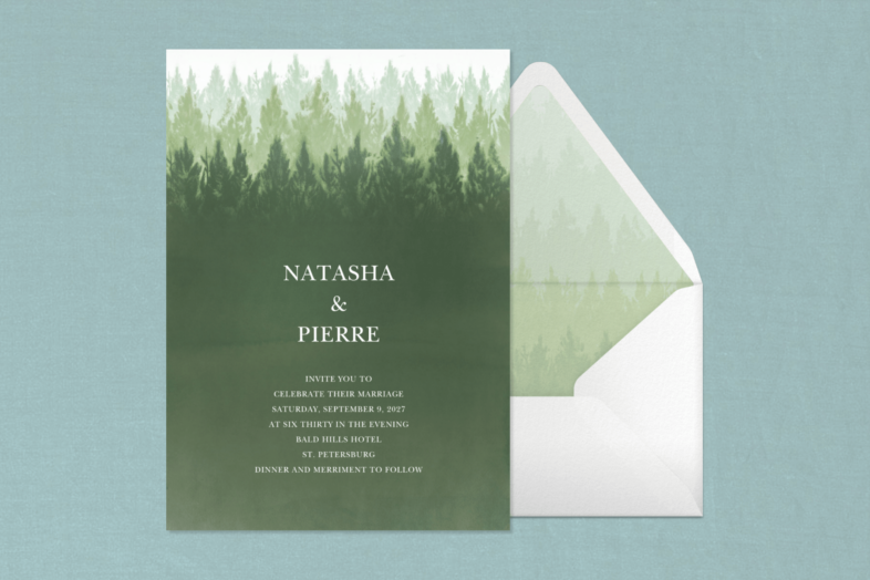 A green invitation with a faded forest illustration beside an envelope with matching liner.
