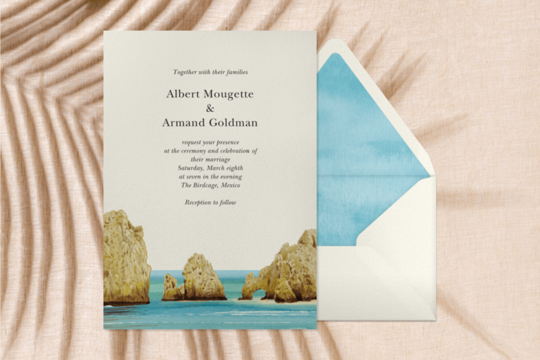 An invitation with an image of three rock formations in the ocean beside an envelope with blue liner.