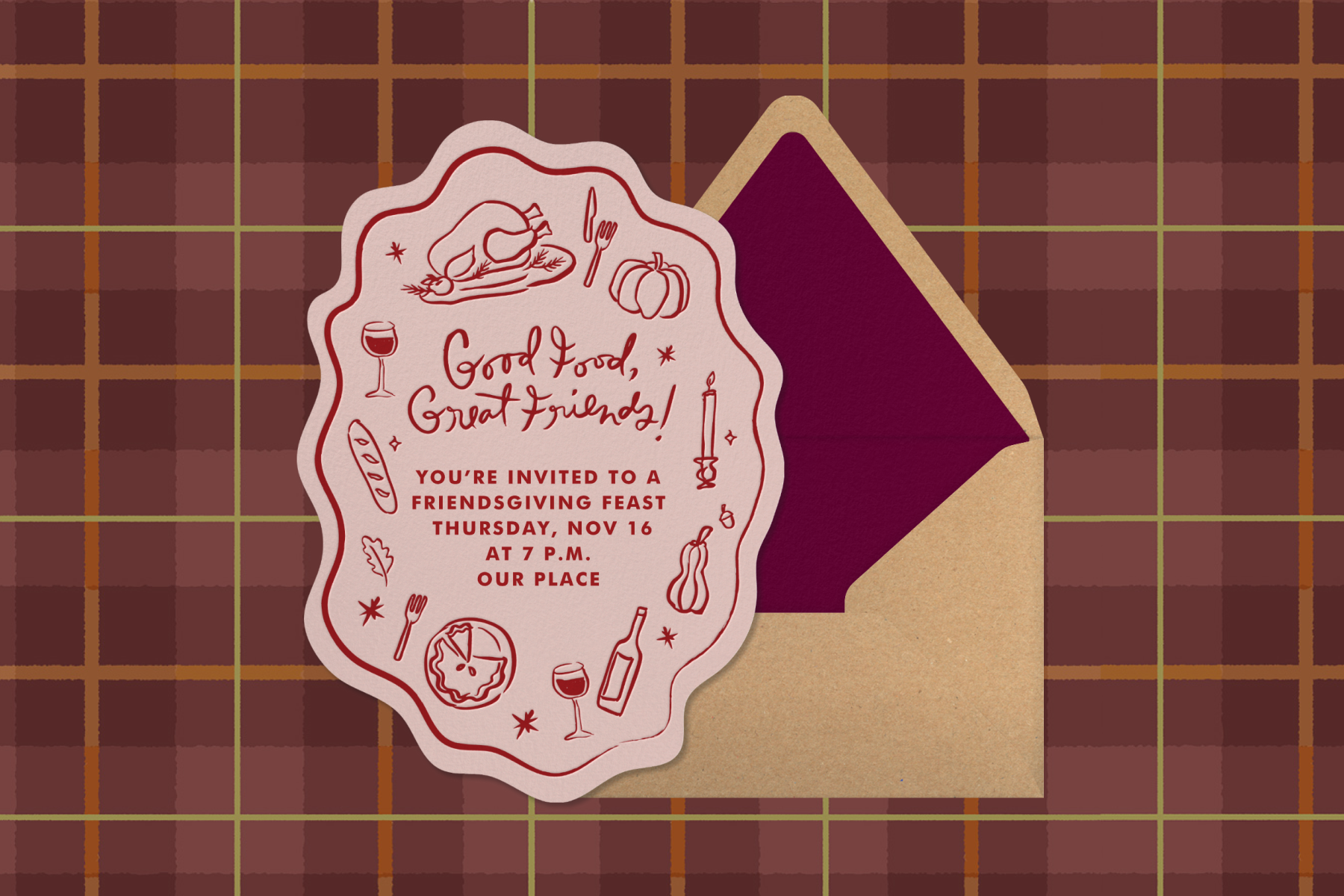 A pink Friendsgiving invitation with wavy edges and red hand-drawn illustrations of a Thanksgiving feast with text reading ‘Good food, great friends!’ sits atop an envelope with a plum liner against a burgundy plaid backdrop.