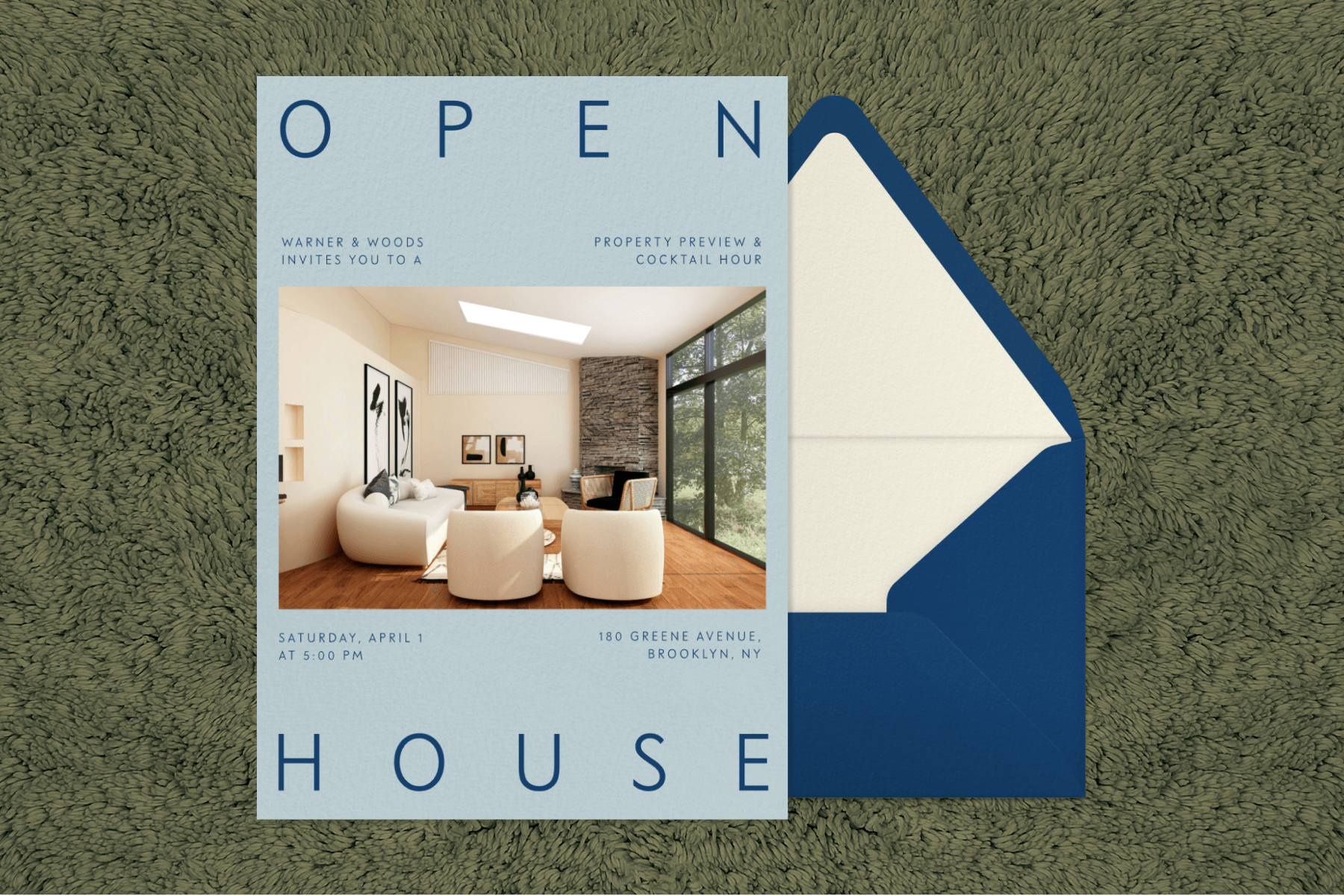 A light blue invitation to an open house showing a modern living room sits on a blue envelope on top of a green, textured backdrop.