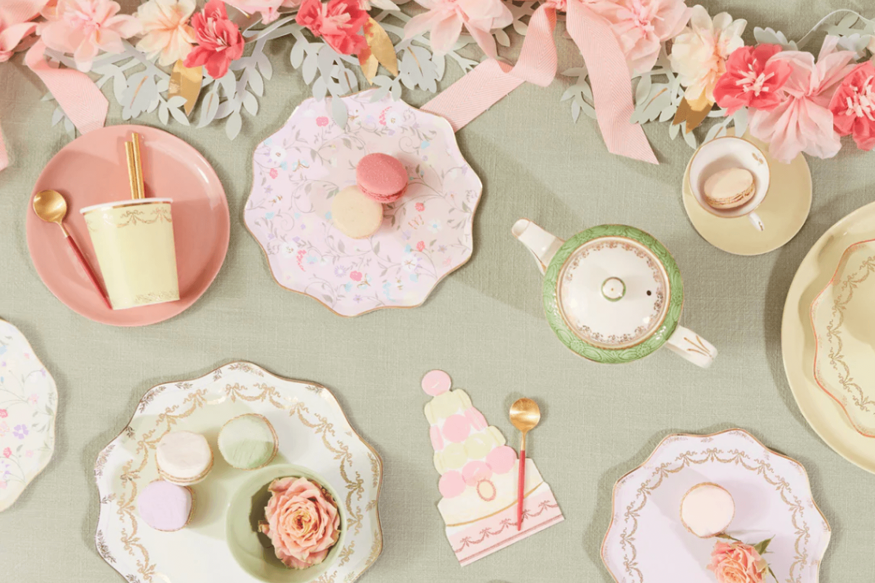 An overhead shot of a Ladurée party table with plates, napkins, a tea pot, flowers, and macarons.