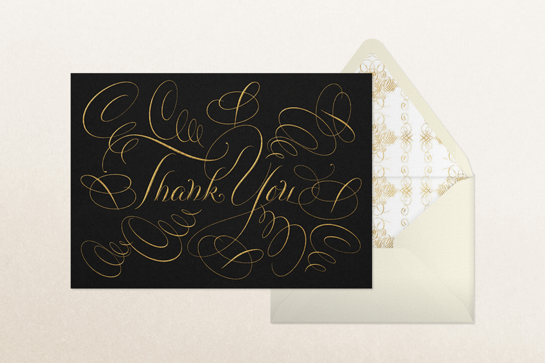 A thank you card with the words written in gold on black in heavily flourished calligraphy.