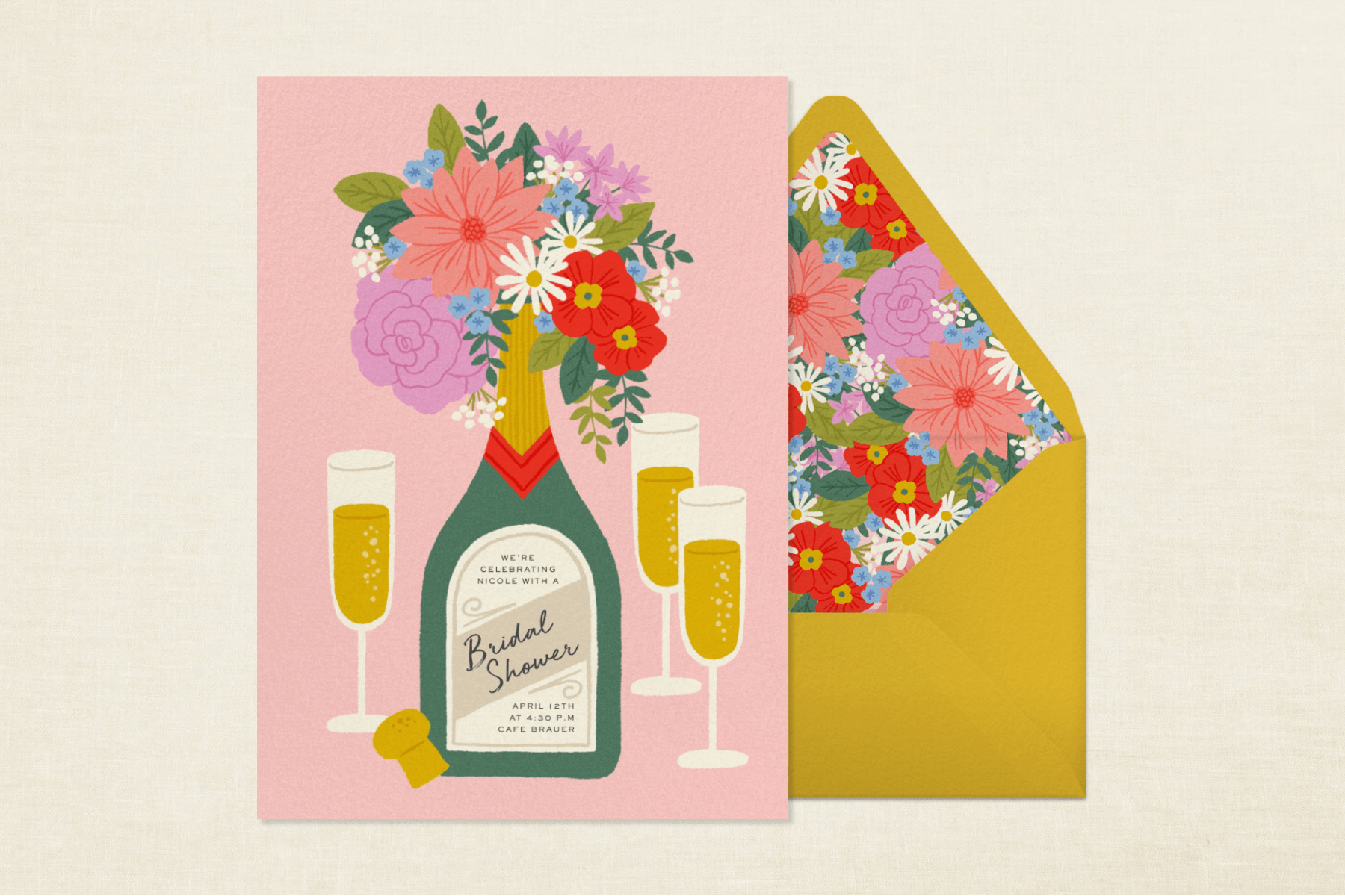 A pink bridal shower invitation on a yellow background features a Champagne bottle with a bouquet inside and three filled Champagne glasses. The invitation sits over a gold envelope with a colorful floral liner.
